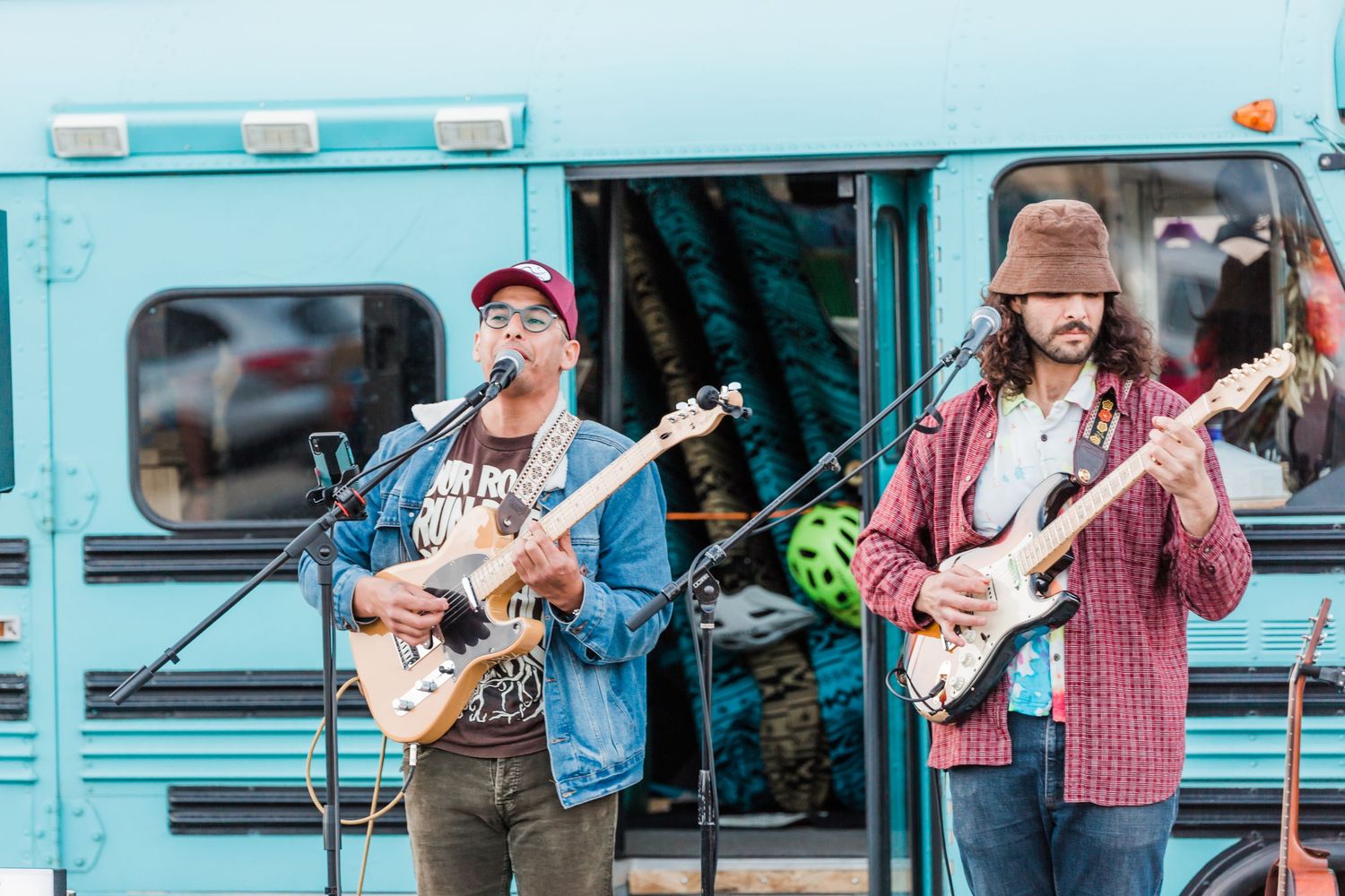 Musicians perform together with guitars and instruments outdoors in a bustling street scene.