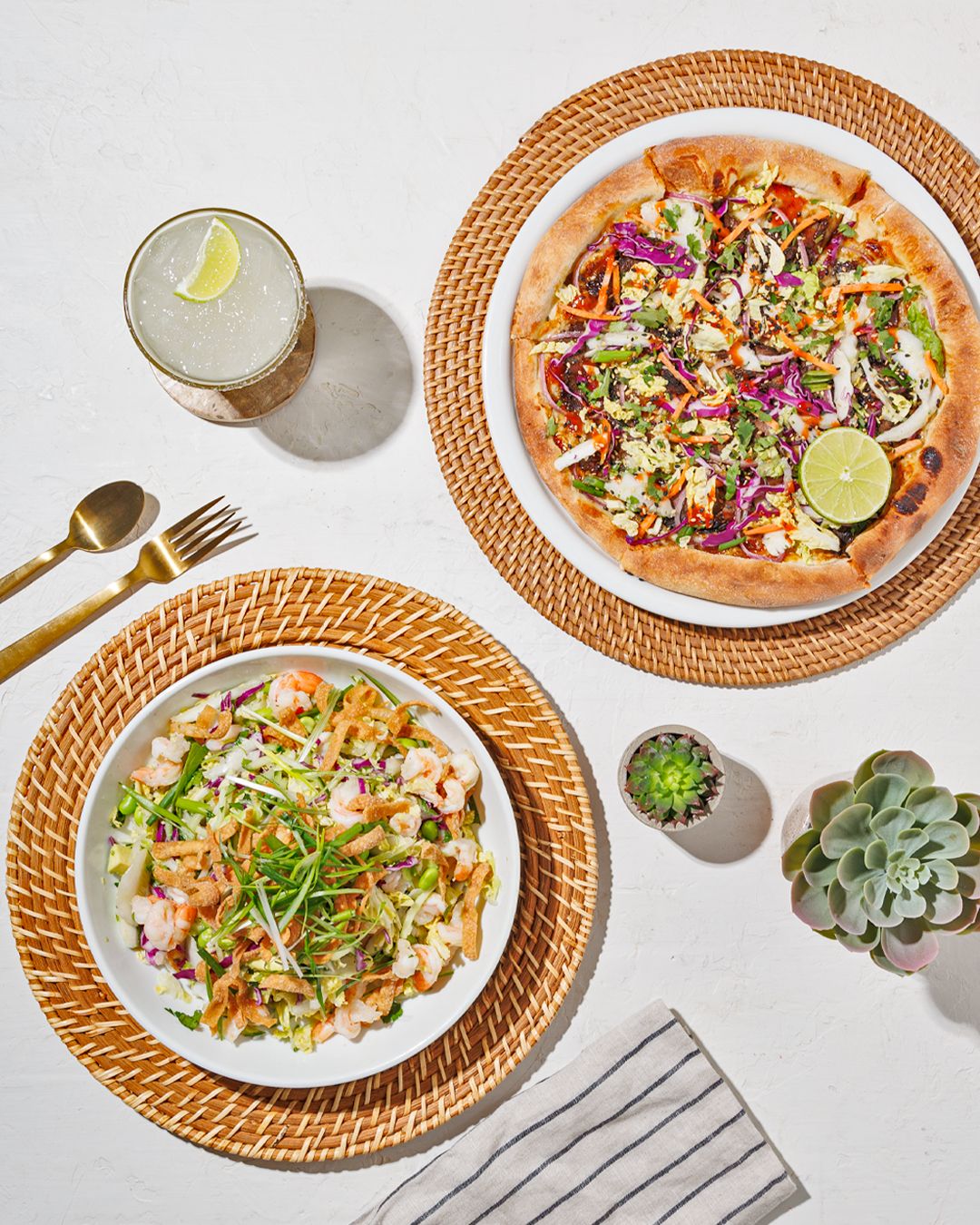 Colorful fish tacos topped with cabbage slaw and fresh herbs on woven placemats.