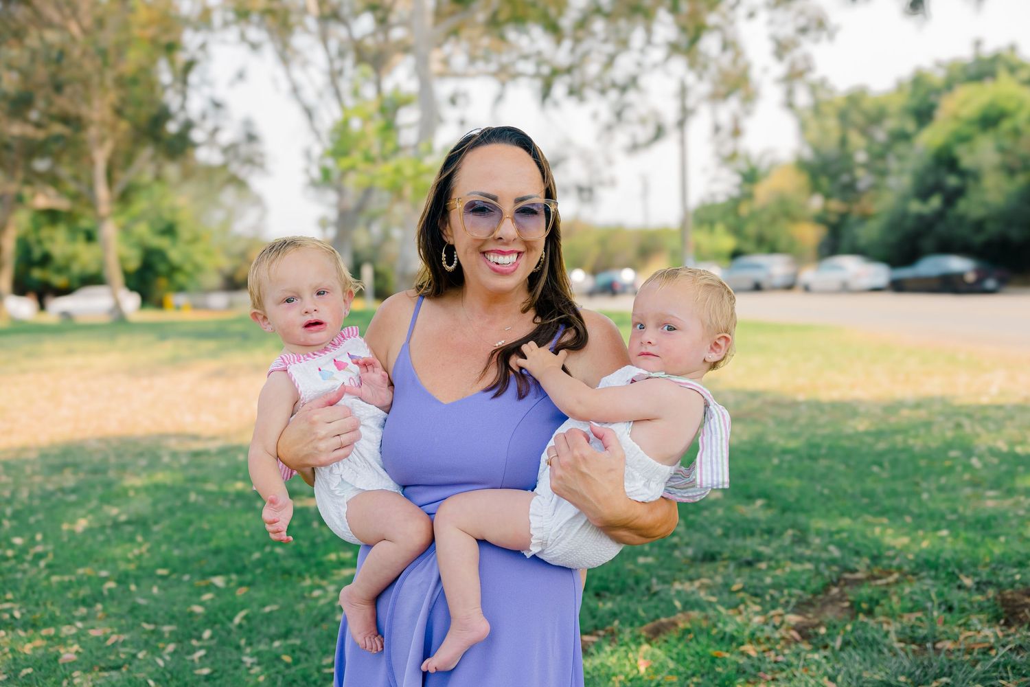 A sunny outdoor family photography session features joyful moments and laughter in a grassy park setting.