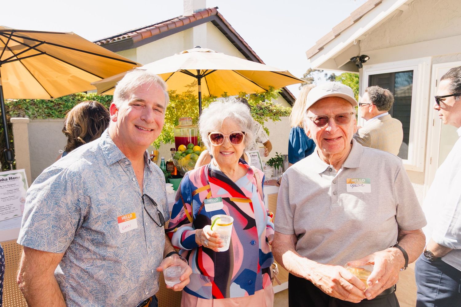 Outdoor party scene with guests mingling under white awnings.