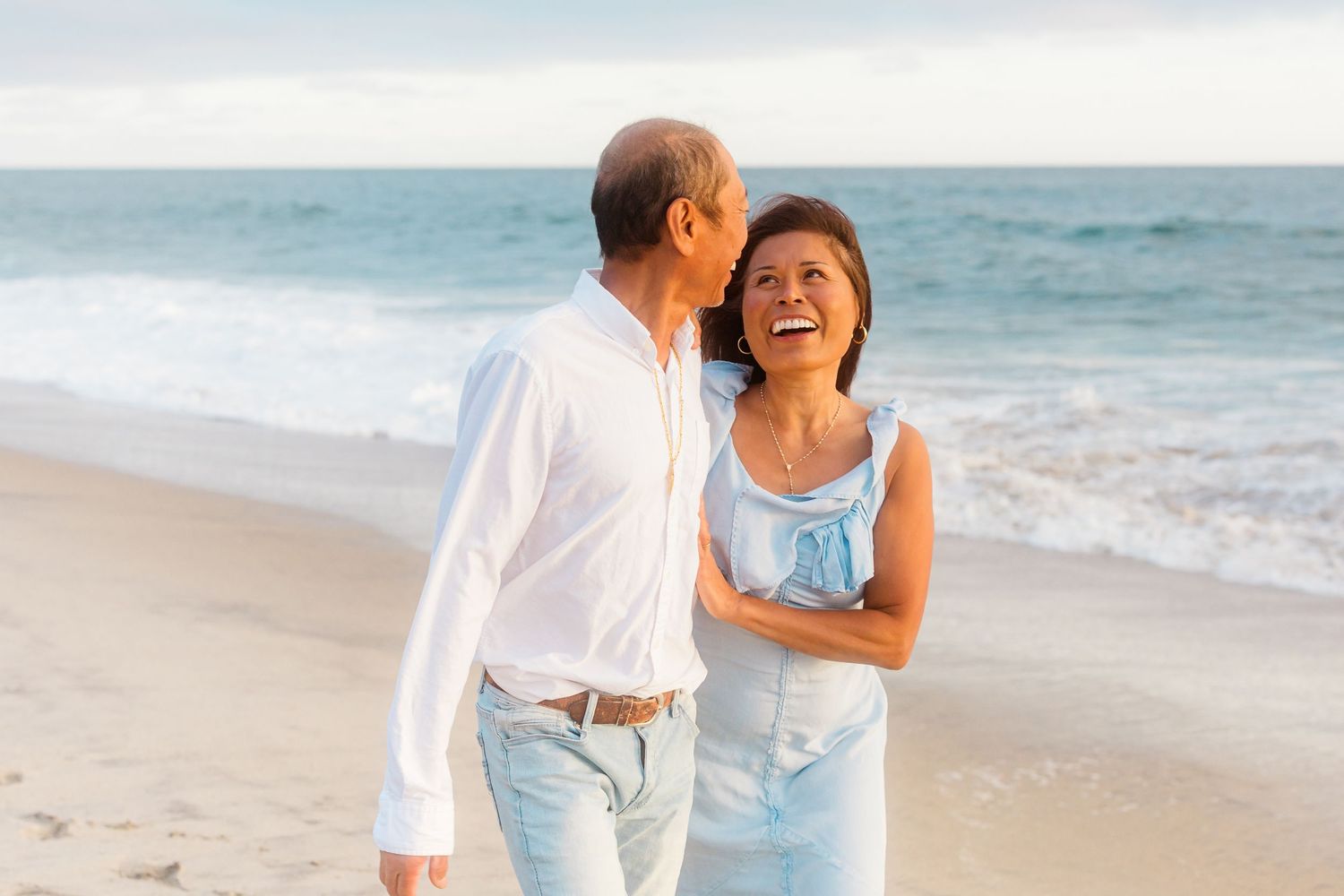 A joyful moment shared between a couple on the beach wearing coordinated outfits.