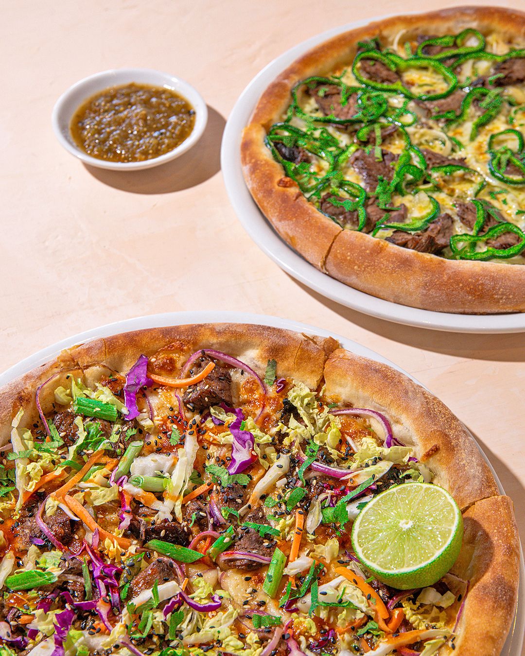 Artisanal pizza topped with fresh greens, red onions and citrus on wooden serving board.