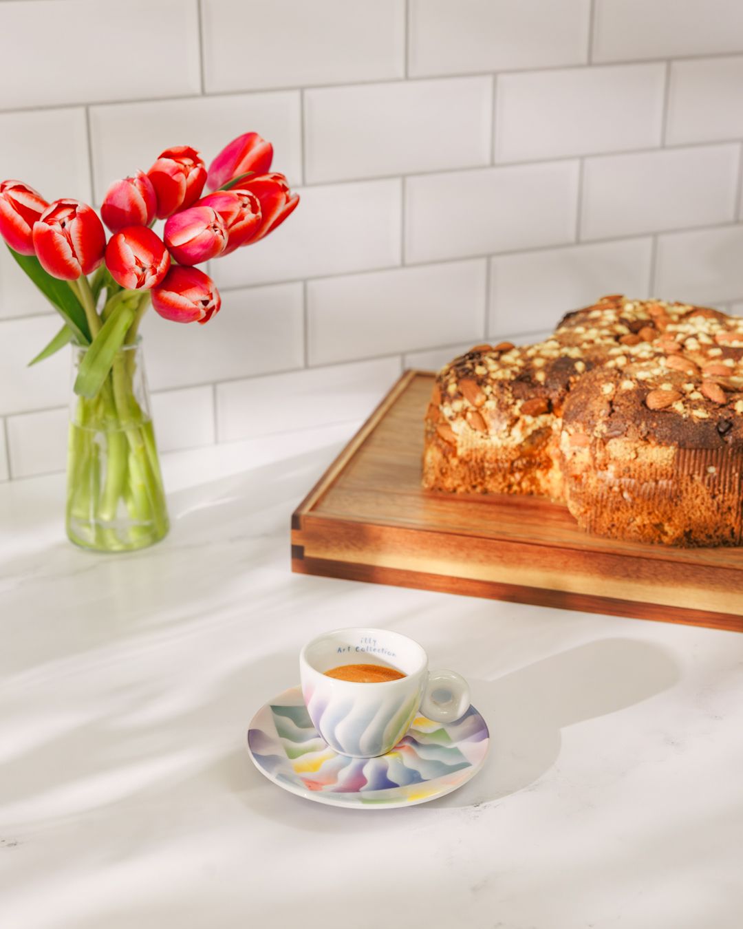Modern kitchen counter with tulips in vase, coffee cup, and fresh baked bread.