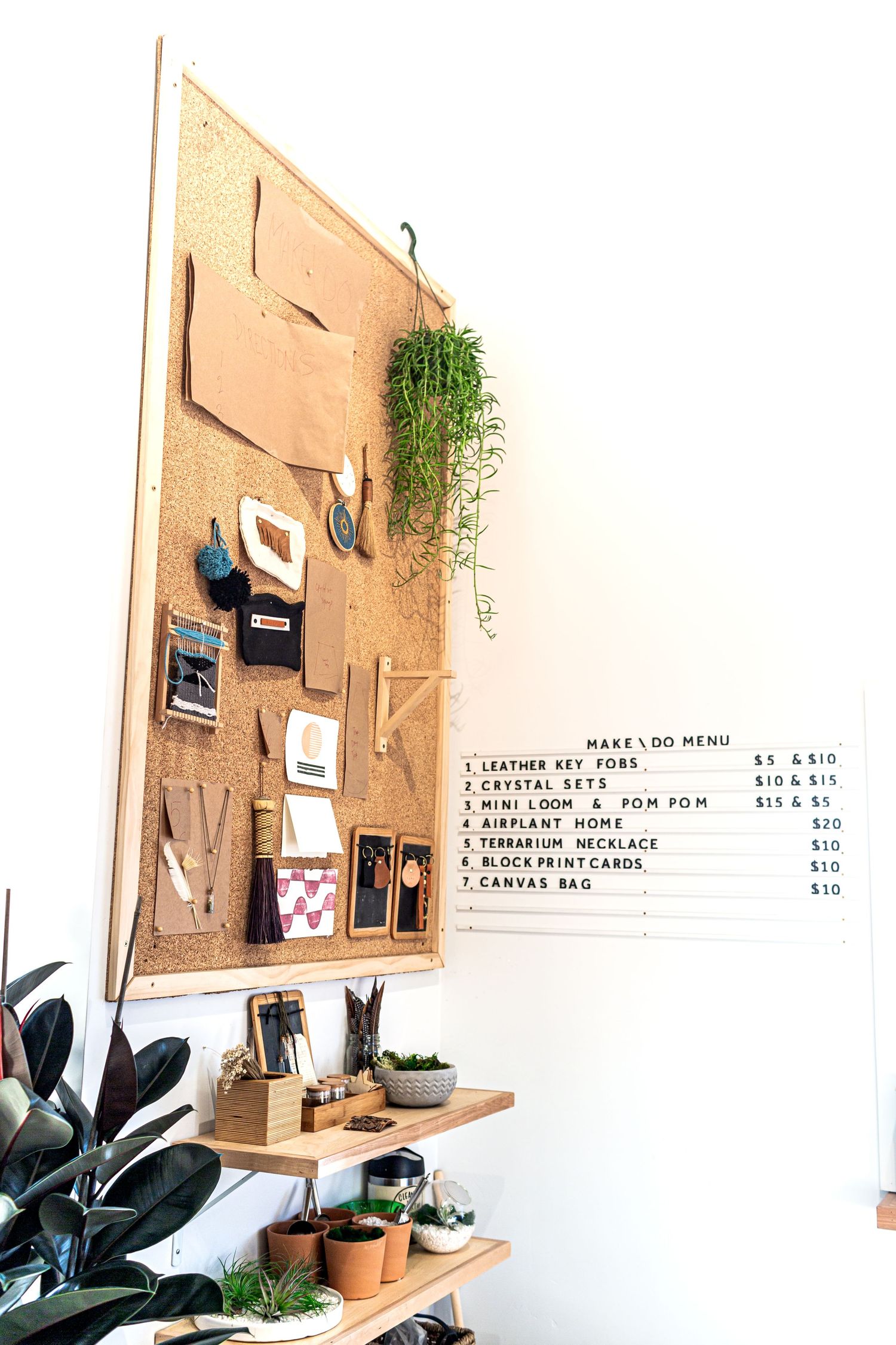 Simple menu board mounted on wood panel wall with green plants and black foliage decorating the minimalist space.