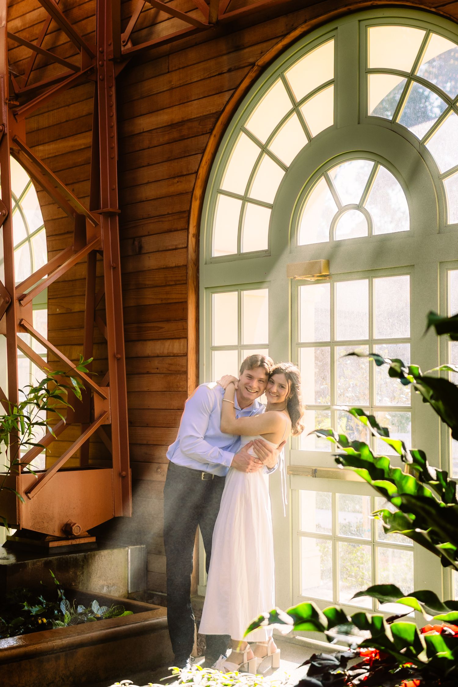 A couple dances in front of large arched windows in a rustic wooden room.