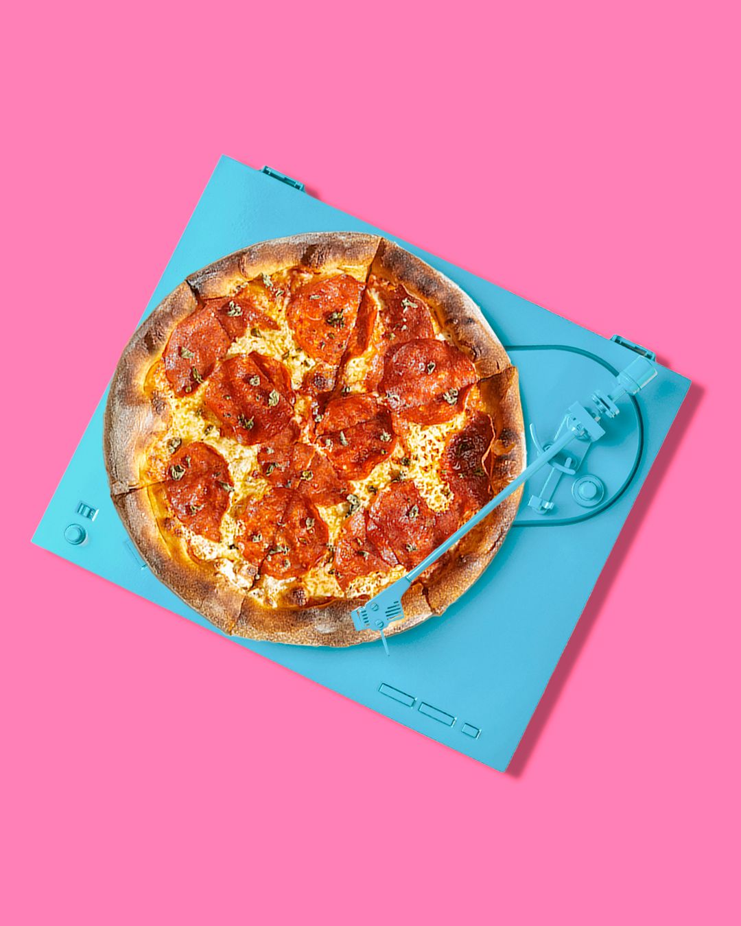 Pizza with pepperoni on blue plate against pink background in minimalist setting.