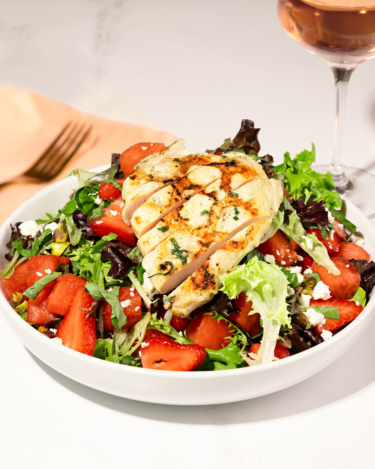 Fresh strawberry salad with mixed greens and nuts served on white plates.