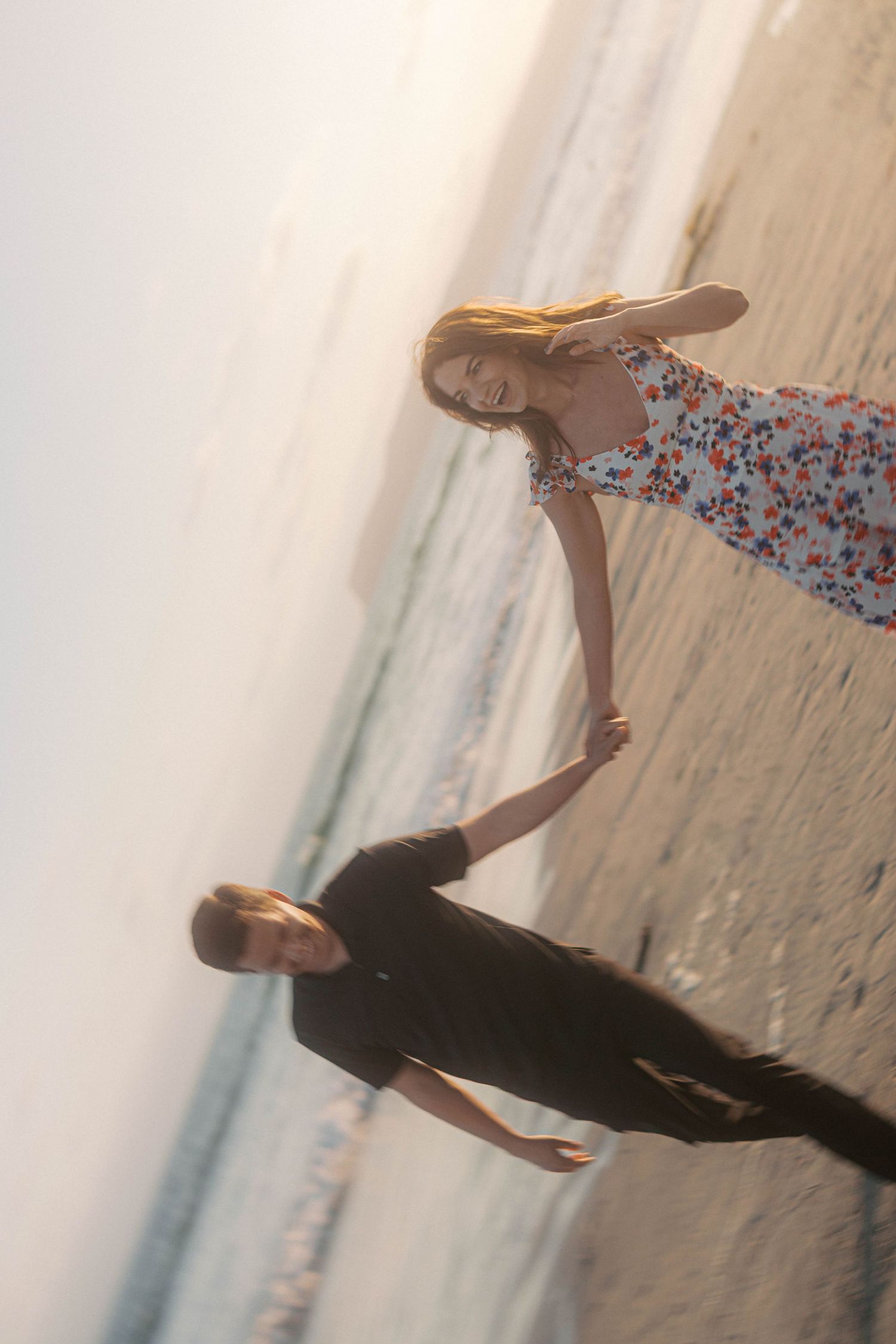A floral dress is caught in motion during a jump sequence on a beach at sunset.