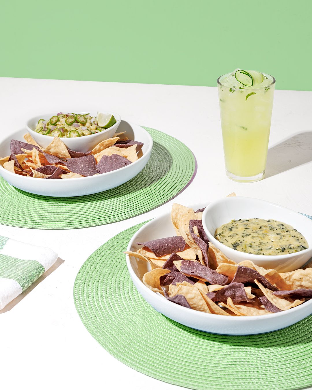 Appetizers and drinks served on a green placemat in bright lighting.