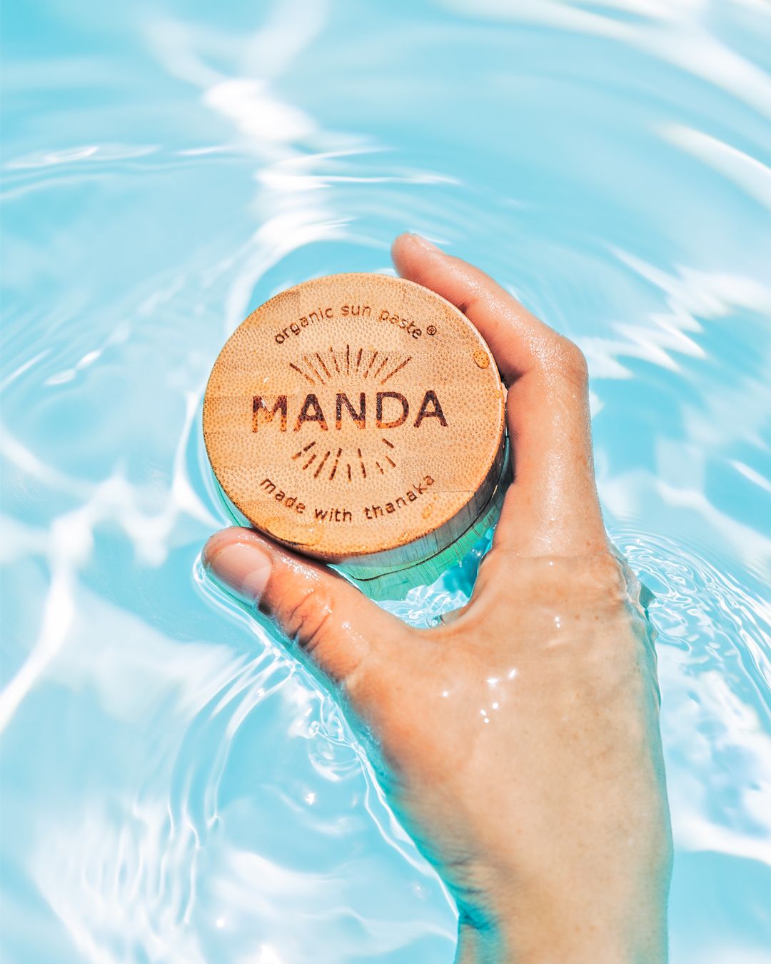 Wooden Manda product lid held over crystal clear swimming pool water.
