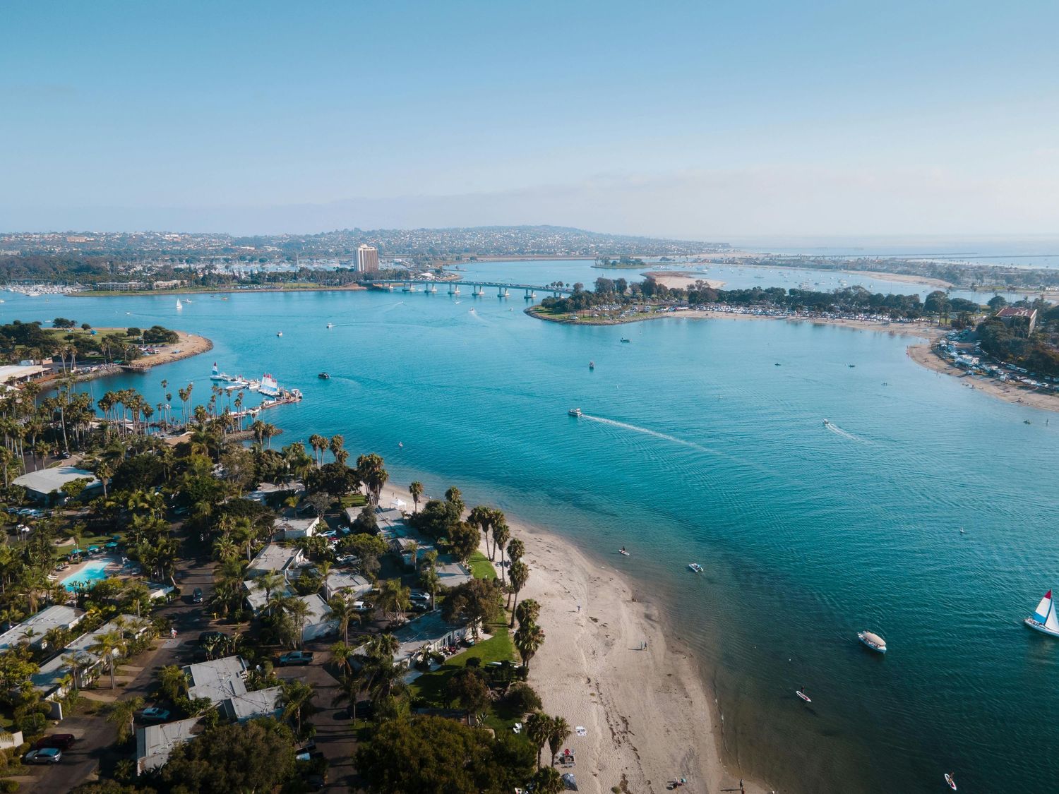 Aerial view of a coastal bay with turquoise waters, boats, and sandy beaches.