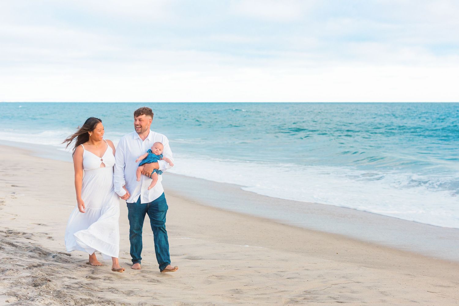 Beautiful beach family photoshoot with gentle waves and clear blue skies.