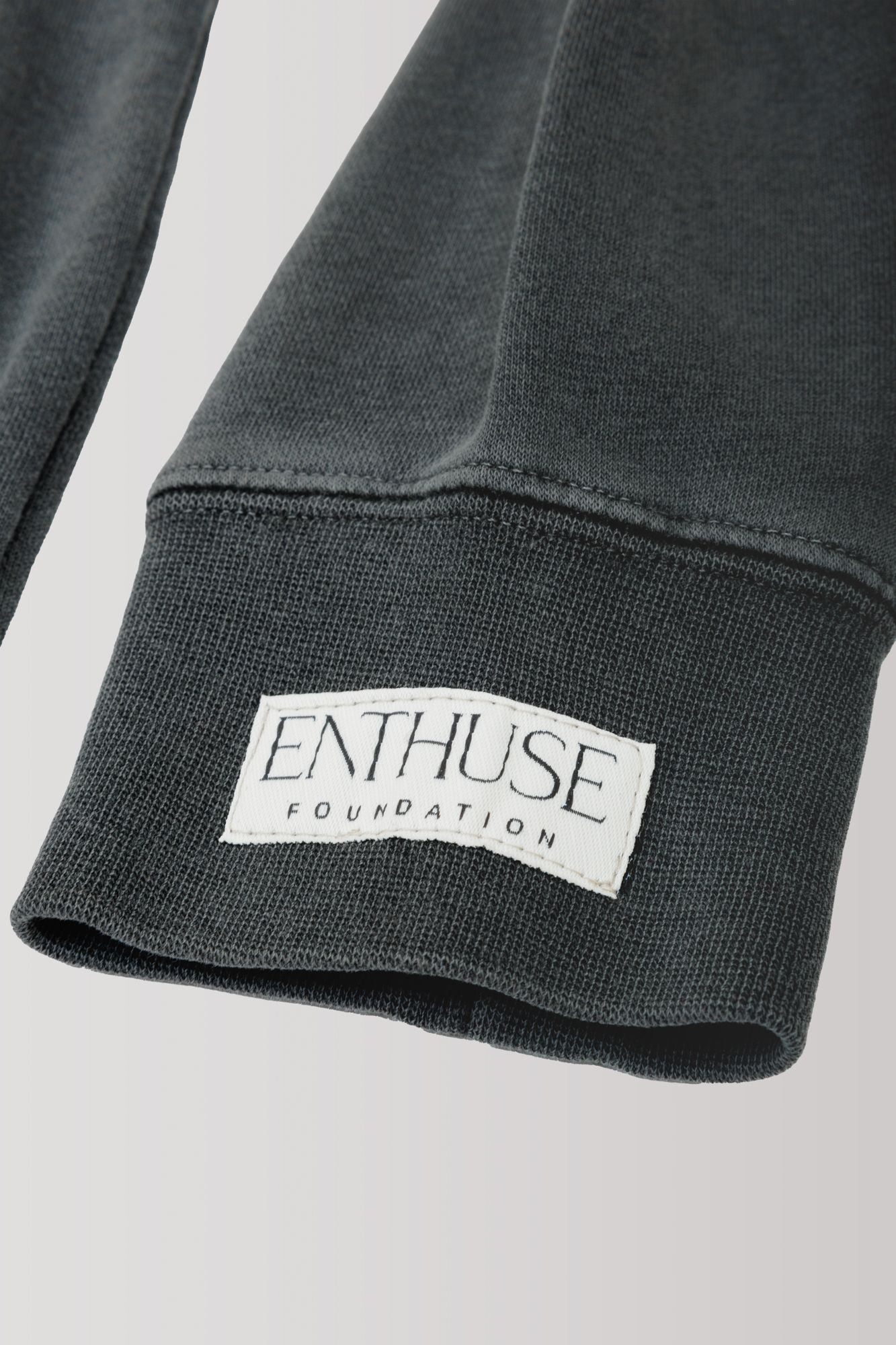 Close-up of grey sweatshirt sleeve showing Enthuse Foundation label.