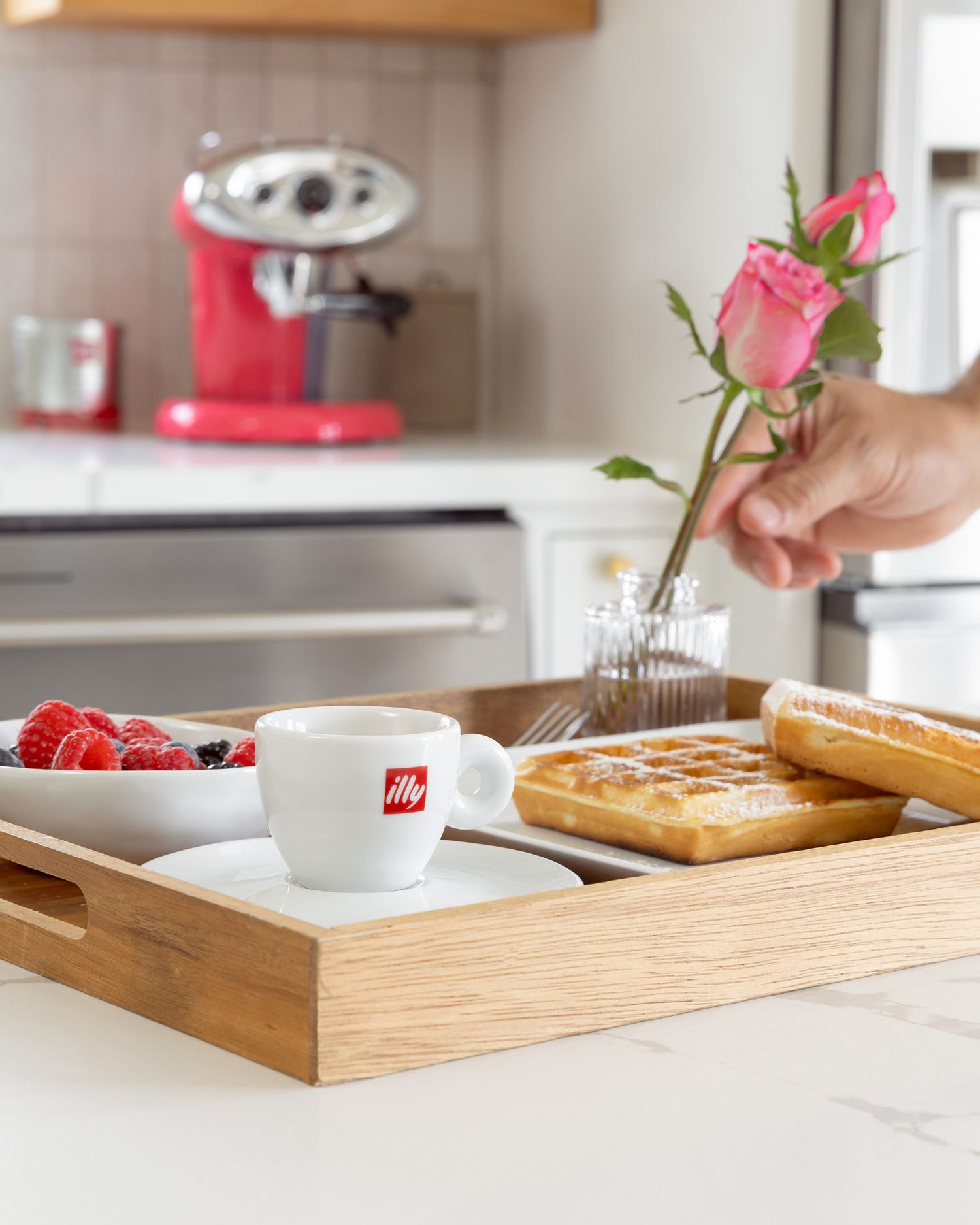 Breakfast tray with illy coffee, waffles, and fresh berries on wooden serving board.