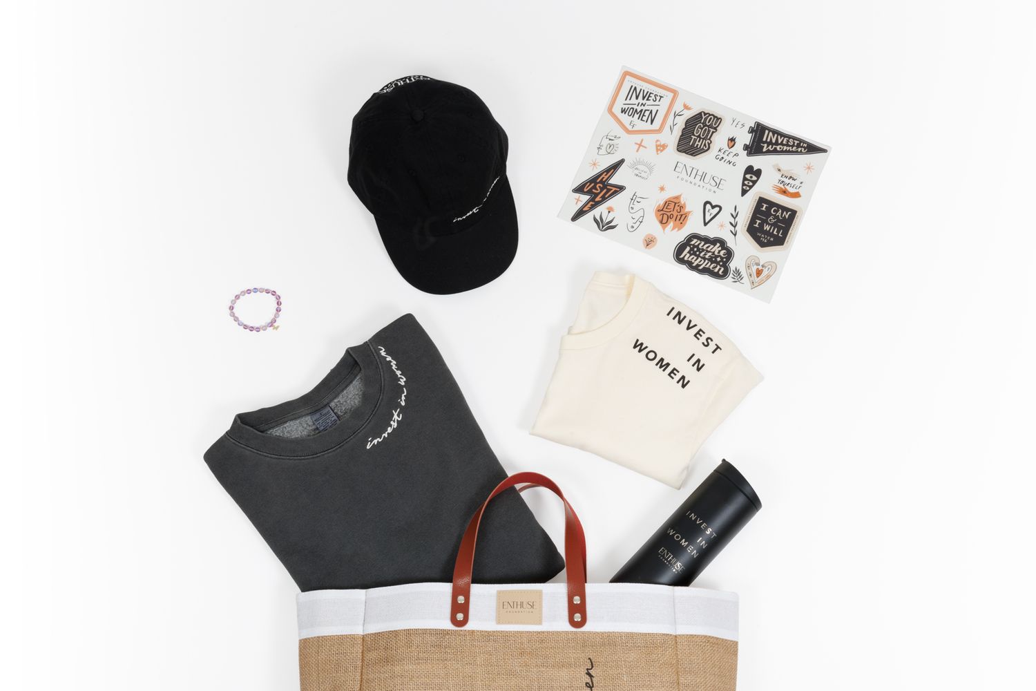 Brown shopping bag with merchandise collection including black cap and stickers.