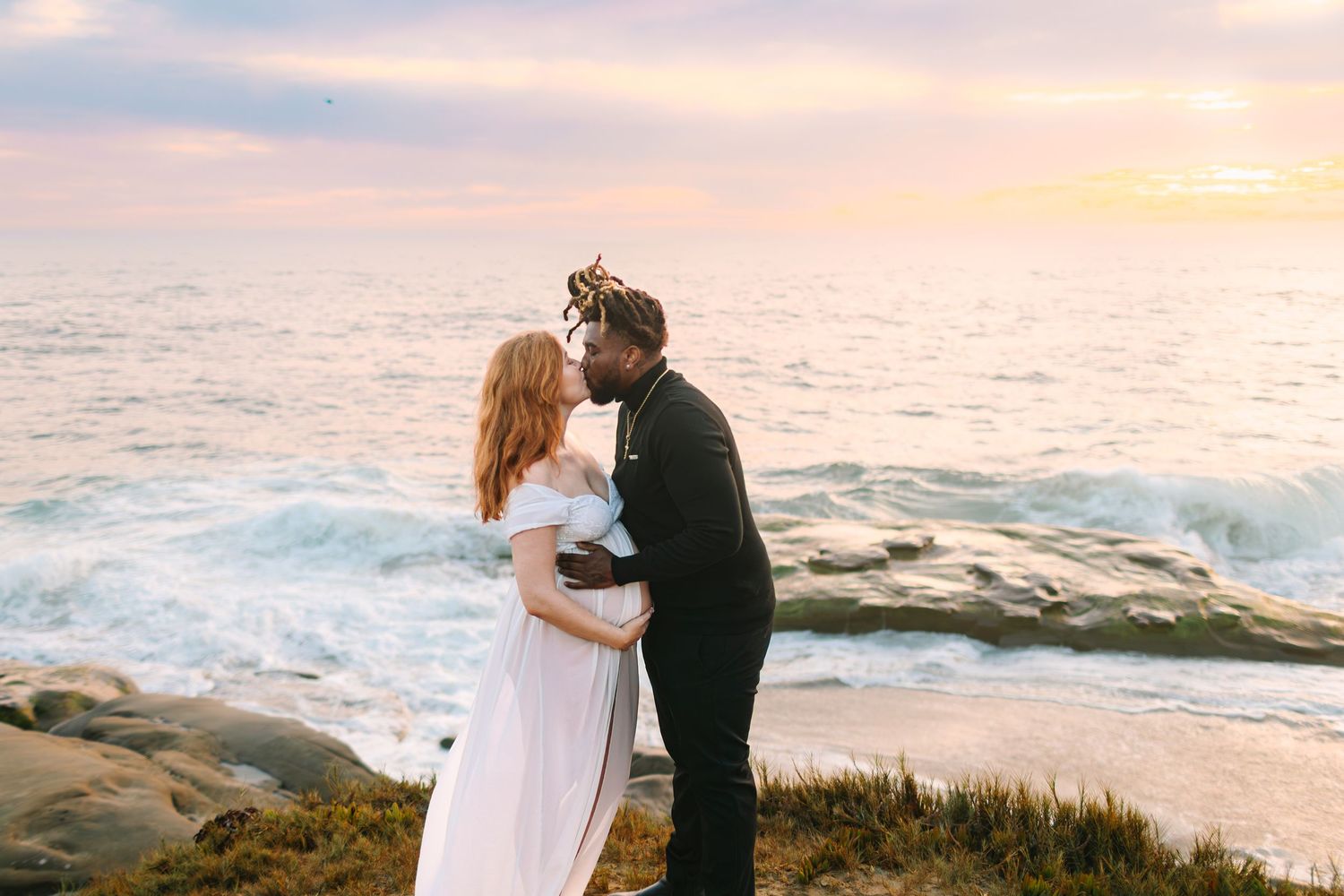 Intimate beachside moment captured against dramatic coastal cliffs during sunset.