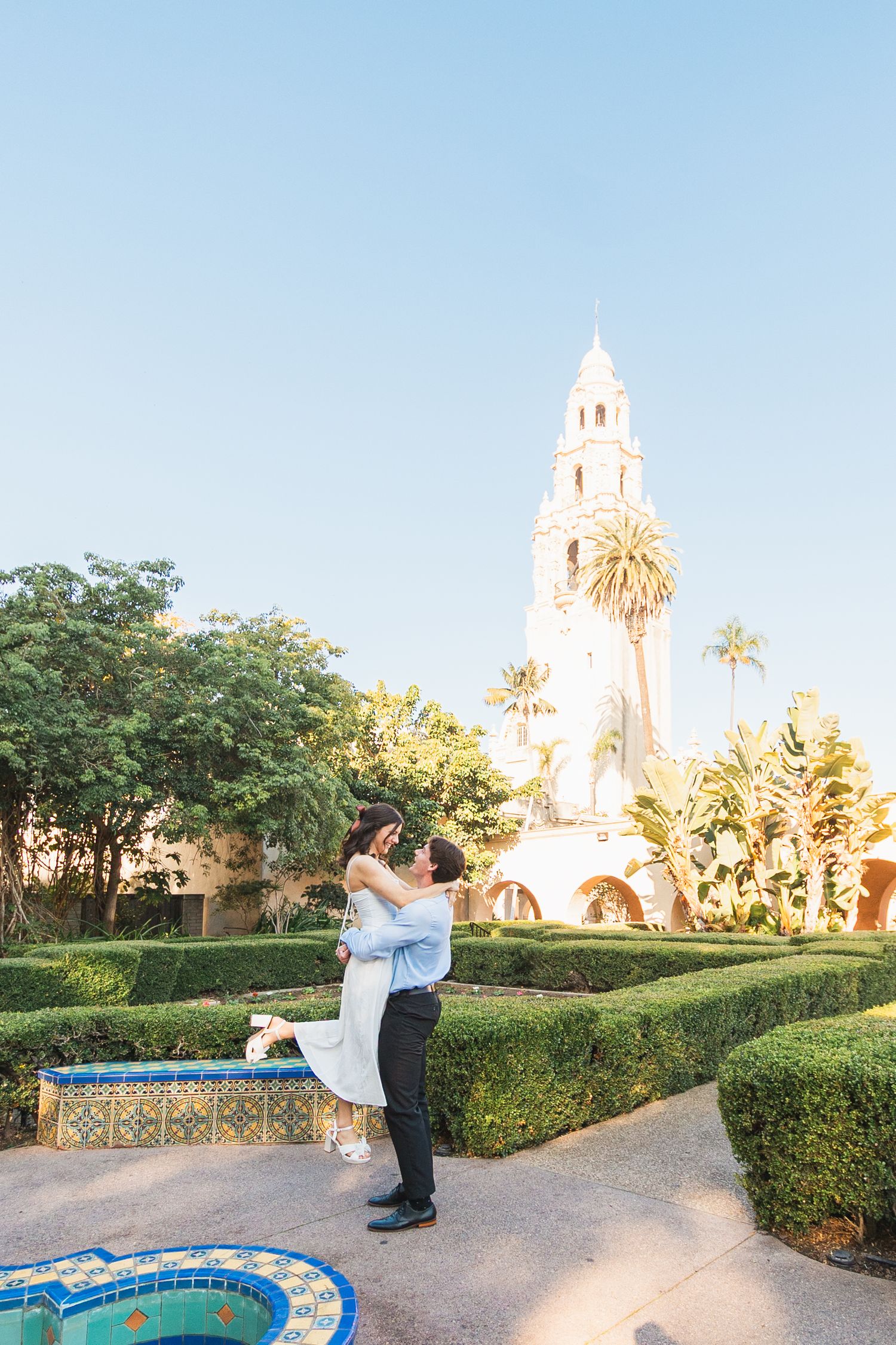 Romantic scene in front of a Spanish colonial style church with palm trees and blue sky.