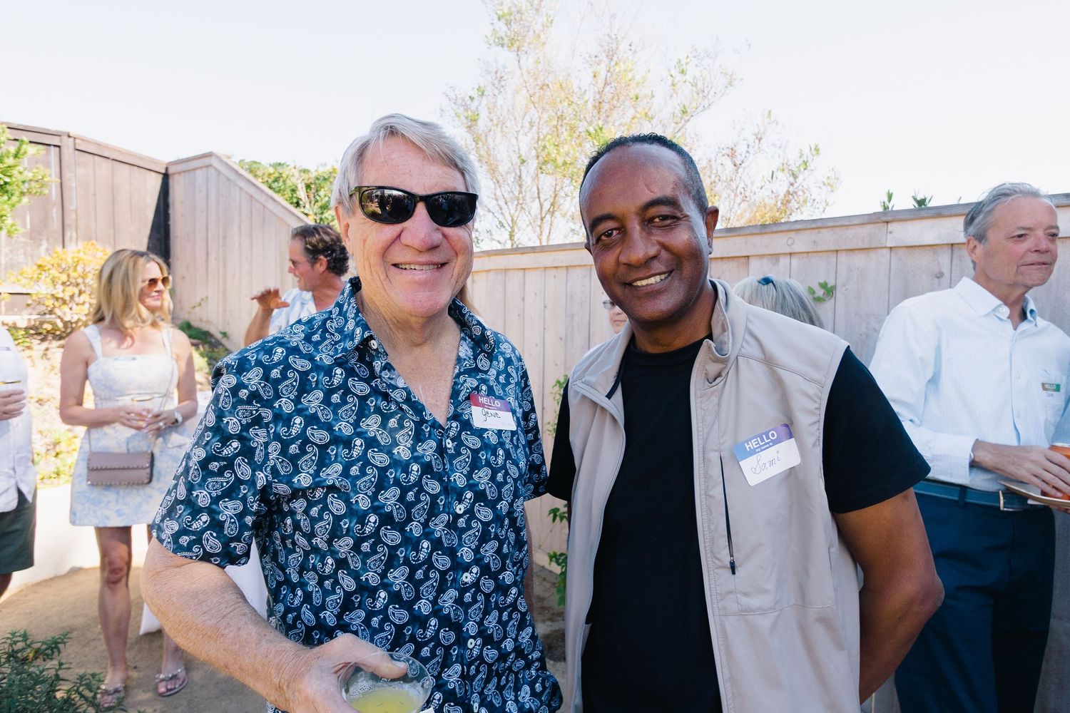A group of people mingling and socializing at a sunny outdoor event.