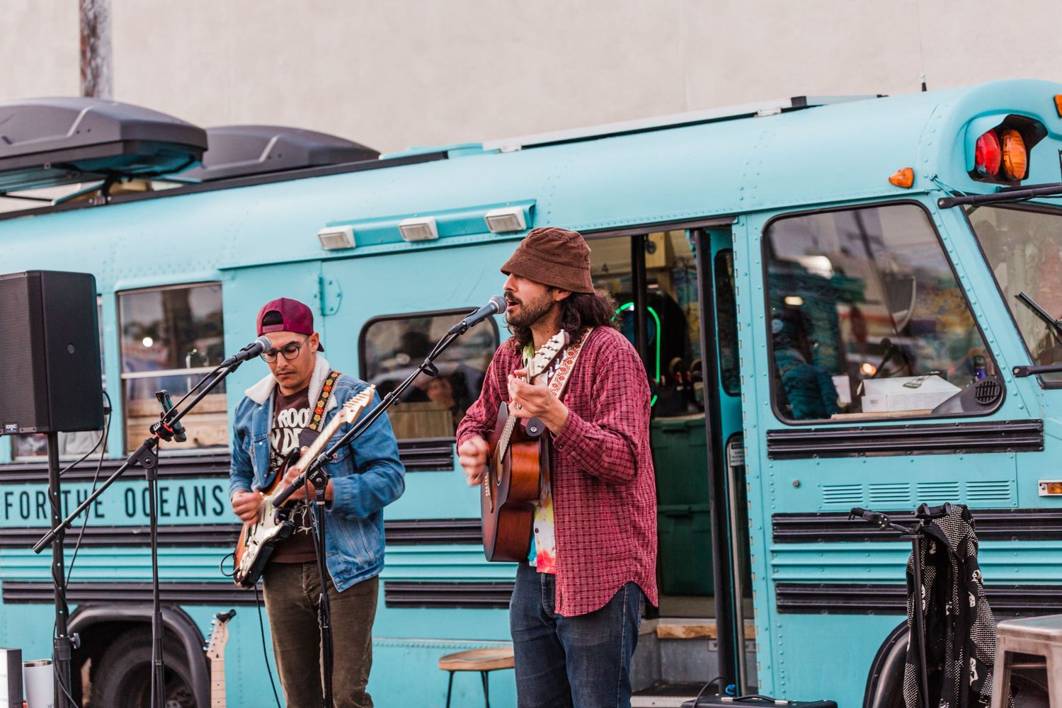 Four colorful retro-style Volkswagen buses are parked in a row during an outdoor event.