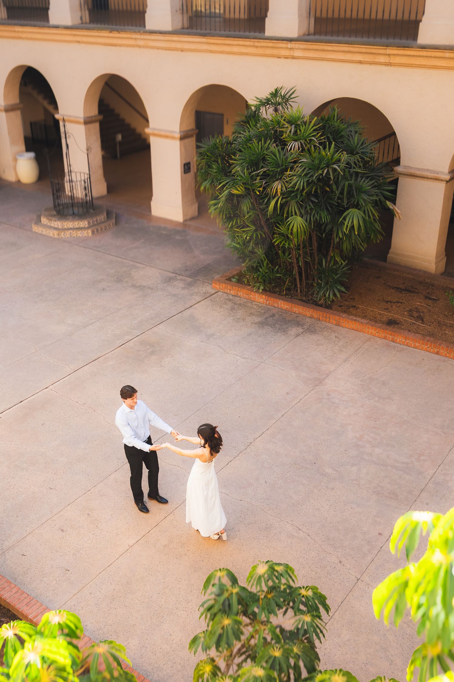 Couple dancing in a Spanish colonial courtyard with arched walkways and tropical plants.