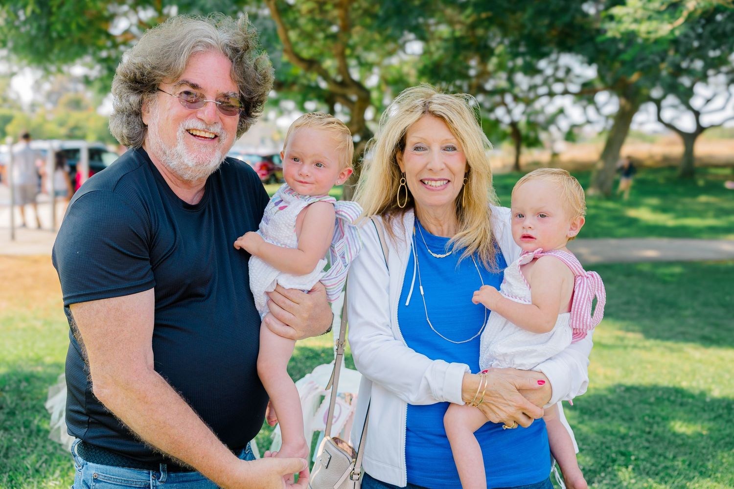 A happy family enjoying quality time together in a sunny park setting with green trees in the background.