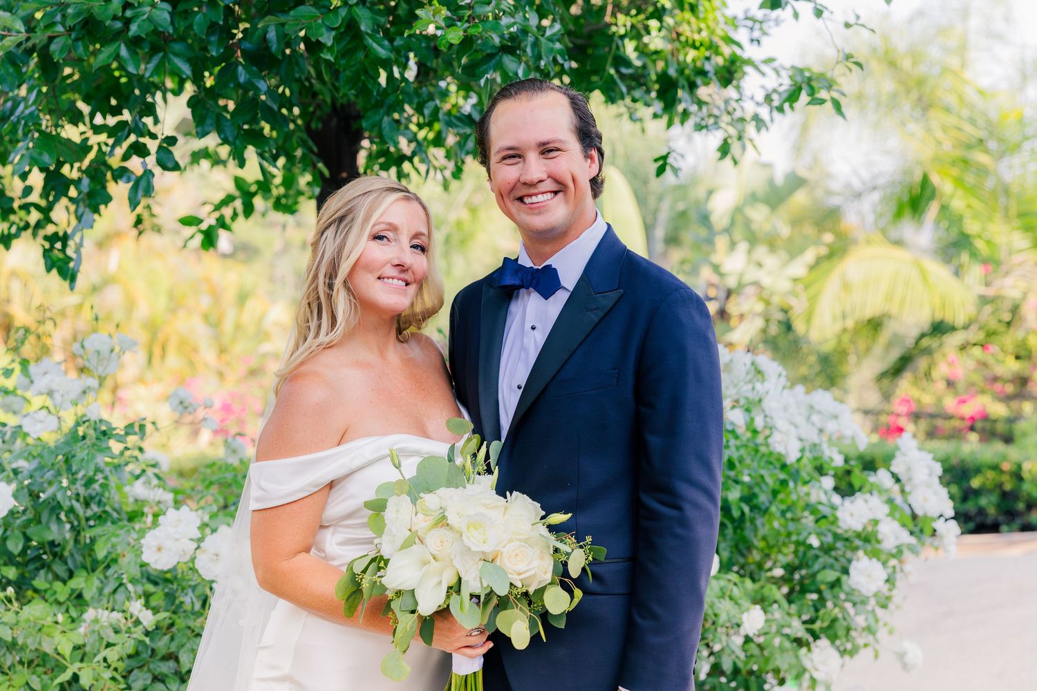 Wedding portraits taken in a garden setting with vibrant green foliage and palm trees.