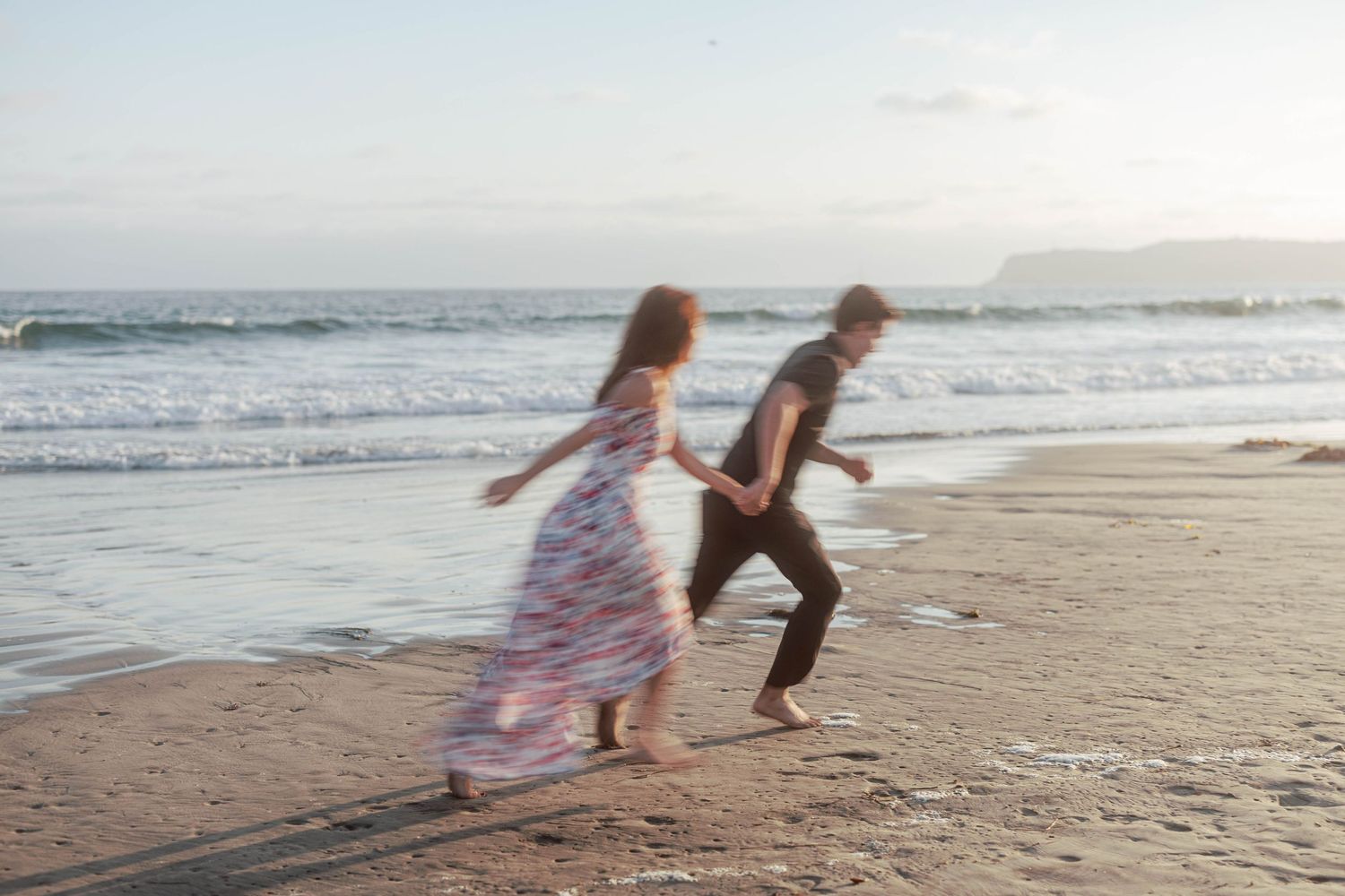 Playful couple running and dancing along the ocean's edge at sunset.