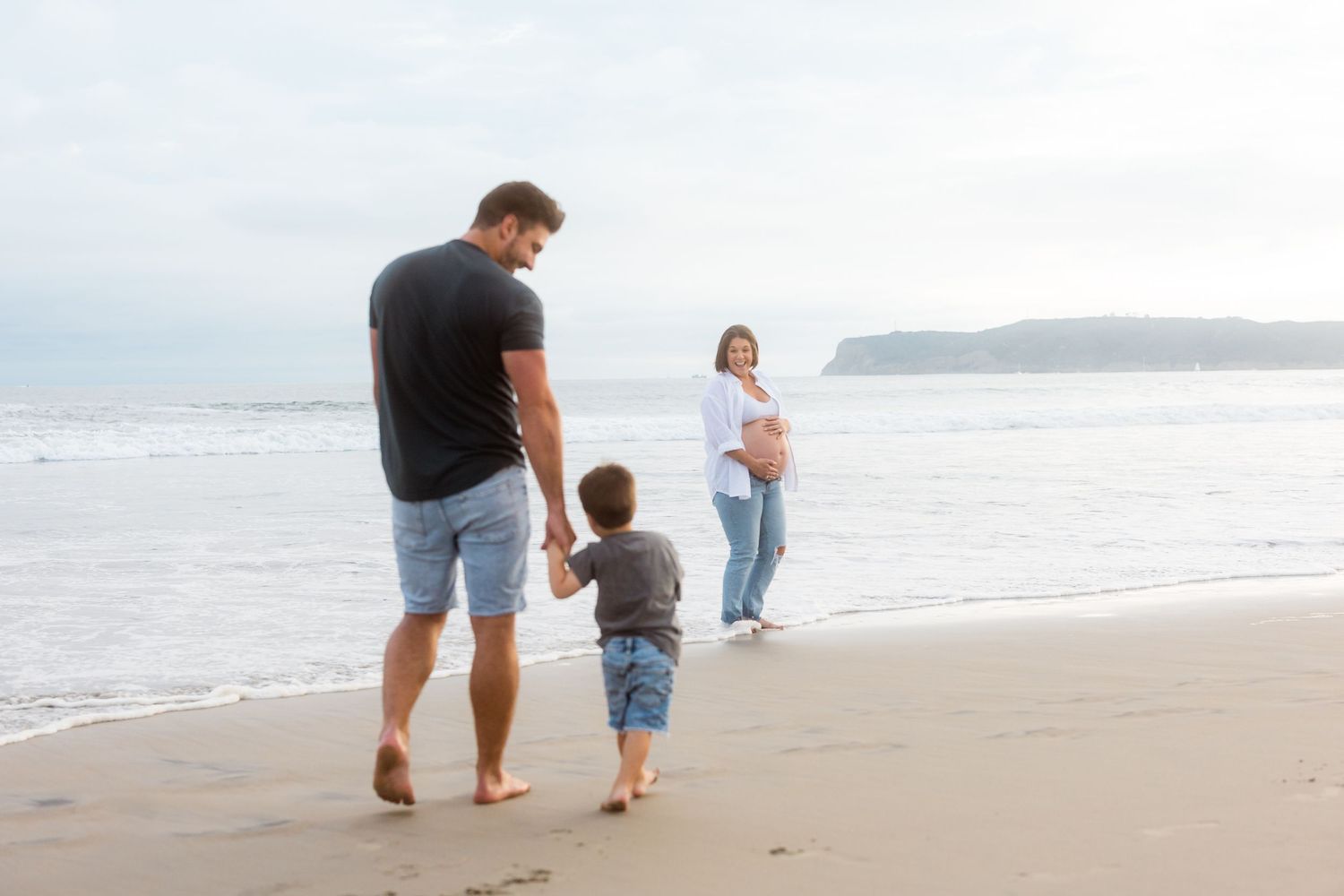 Family walking together on a peaceful beach during golden hour.