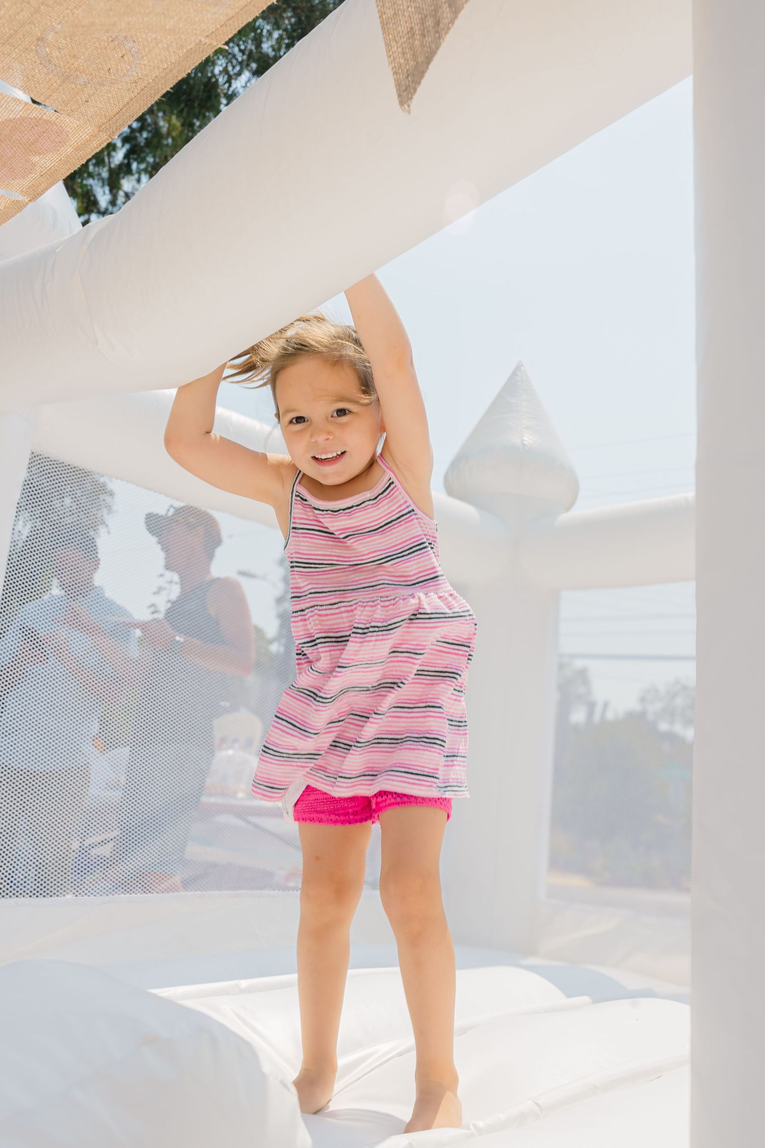 Child in a striped pink top enjoying playtime with balls in a bright indoor setting.