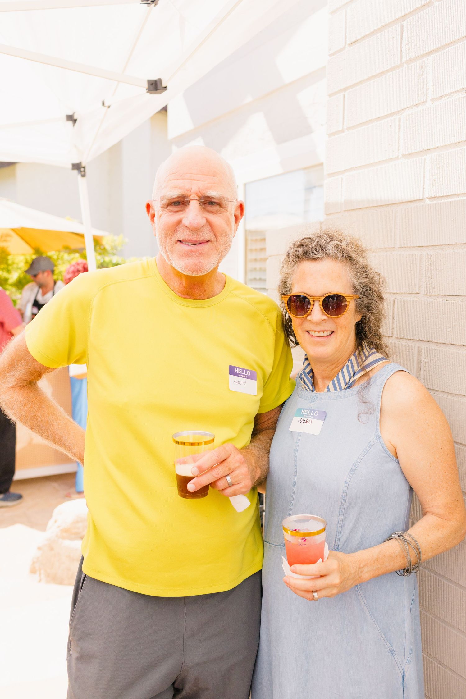 A couple in casual attire enjoying refreshments together at an outdoor gathering.