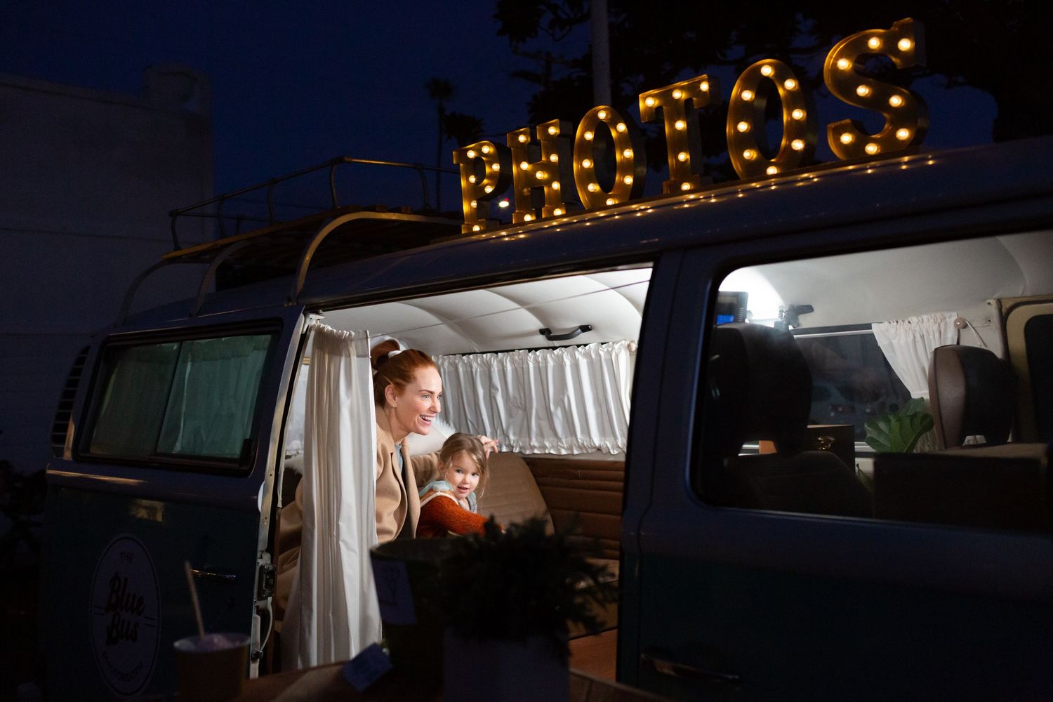 Illuminated RV camper parked at night with interior lights glowing through the windows and open door.