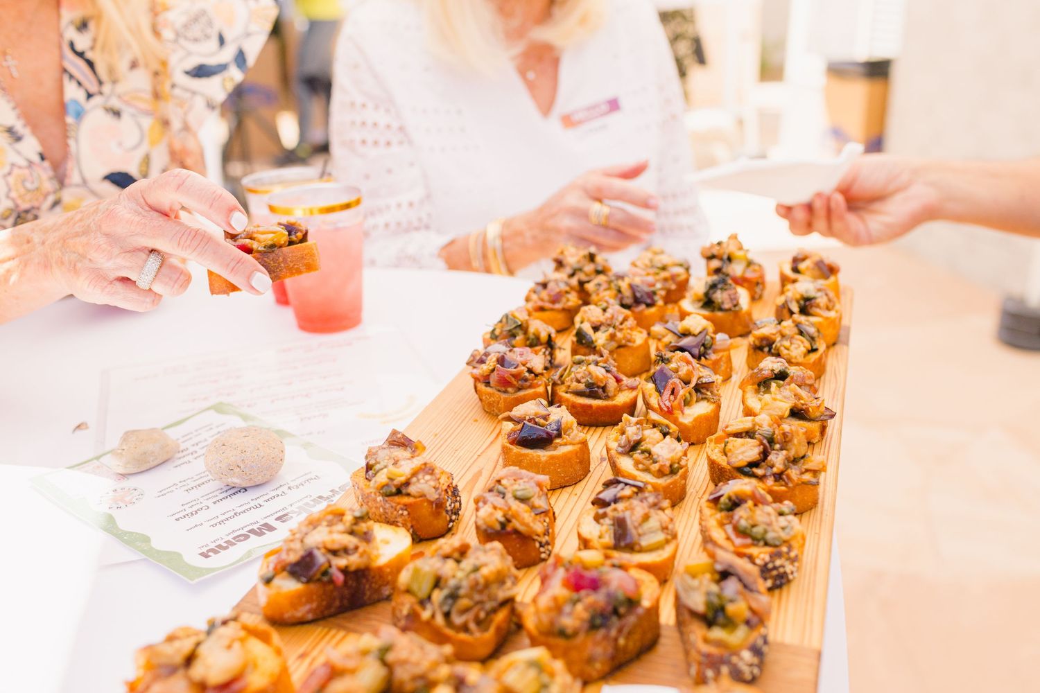 Appetizing array of golden-brown pastries and hors d'oeuvres displayed on serving platters at an outdoor event.