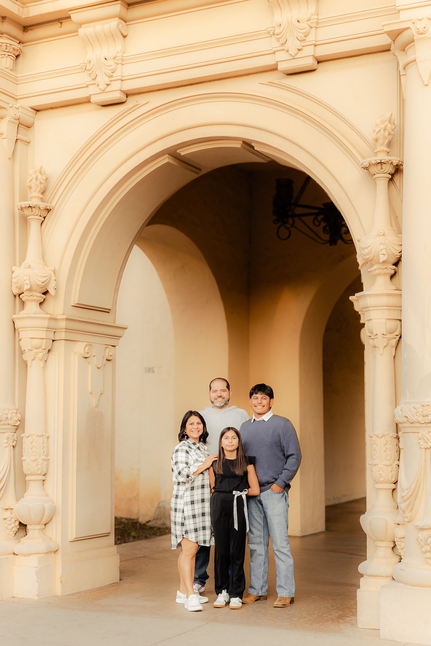 Family poses under elegant white archways at Balboa Park in San Diego during outdoor photo session.