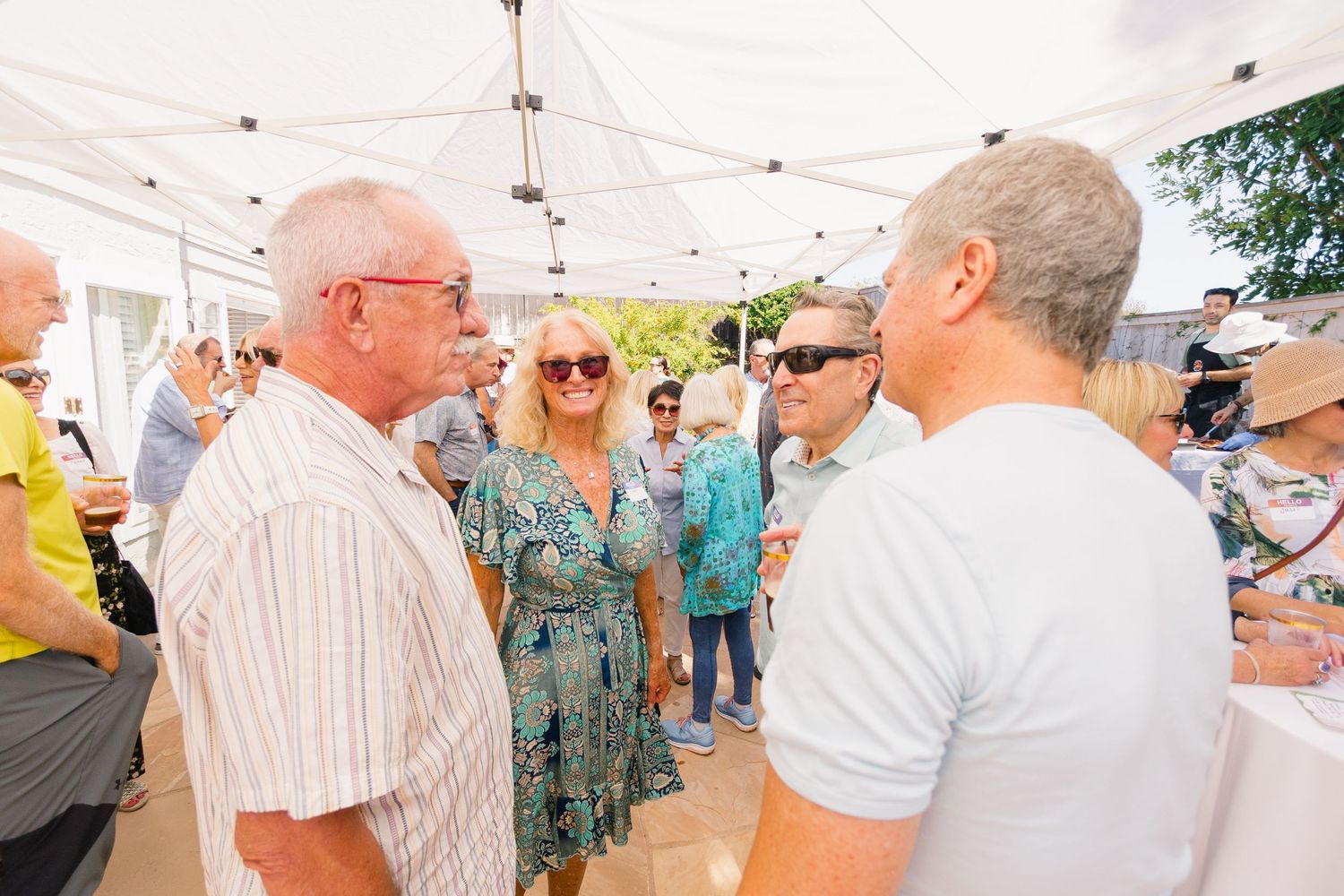 Guests socializing and holding drinks at a casual outdoor gathering.