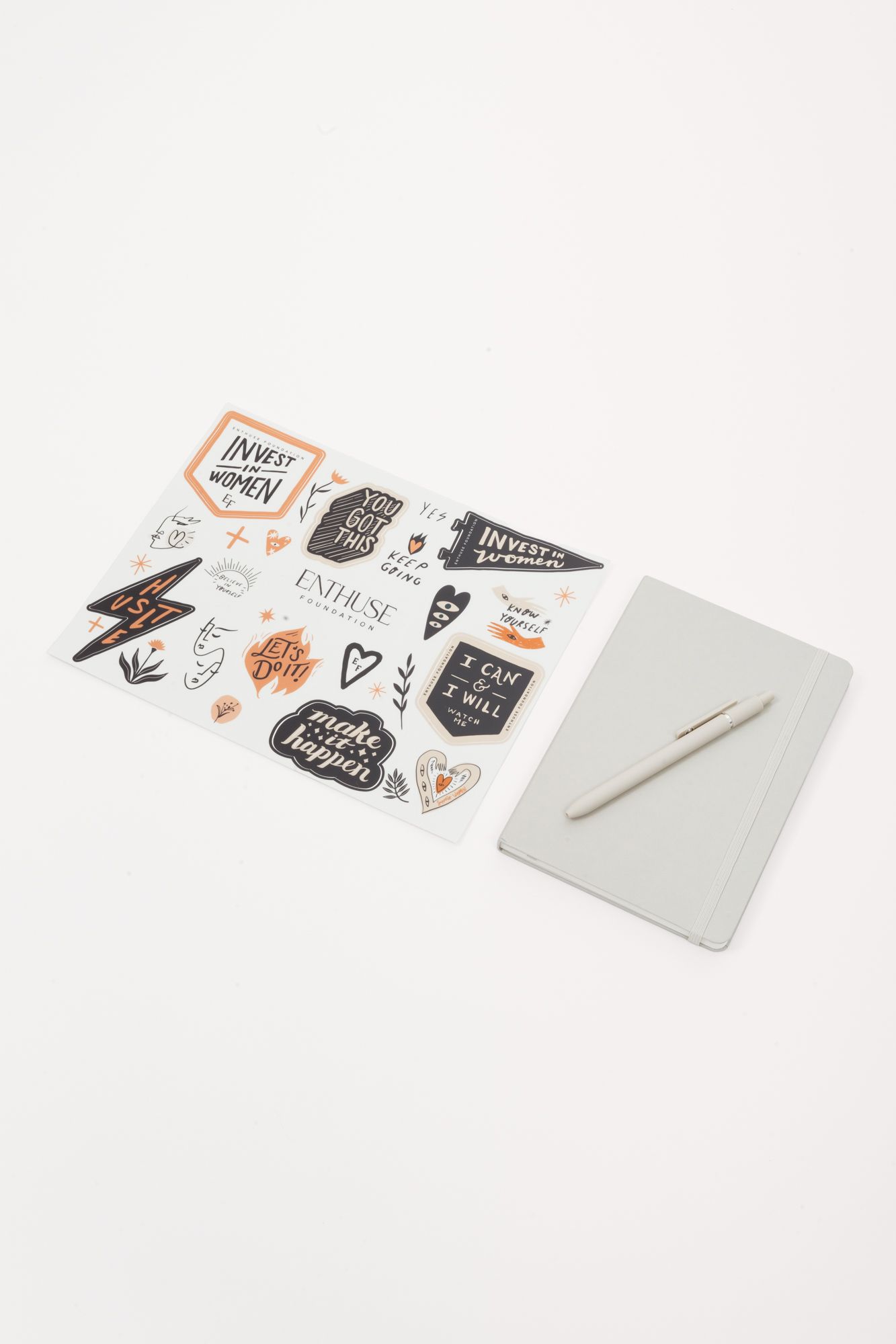 Sheet of black and orange stickers displayed next to blank notepad and pen.