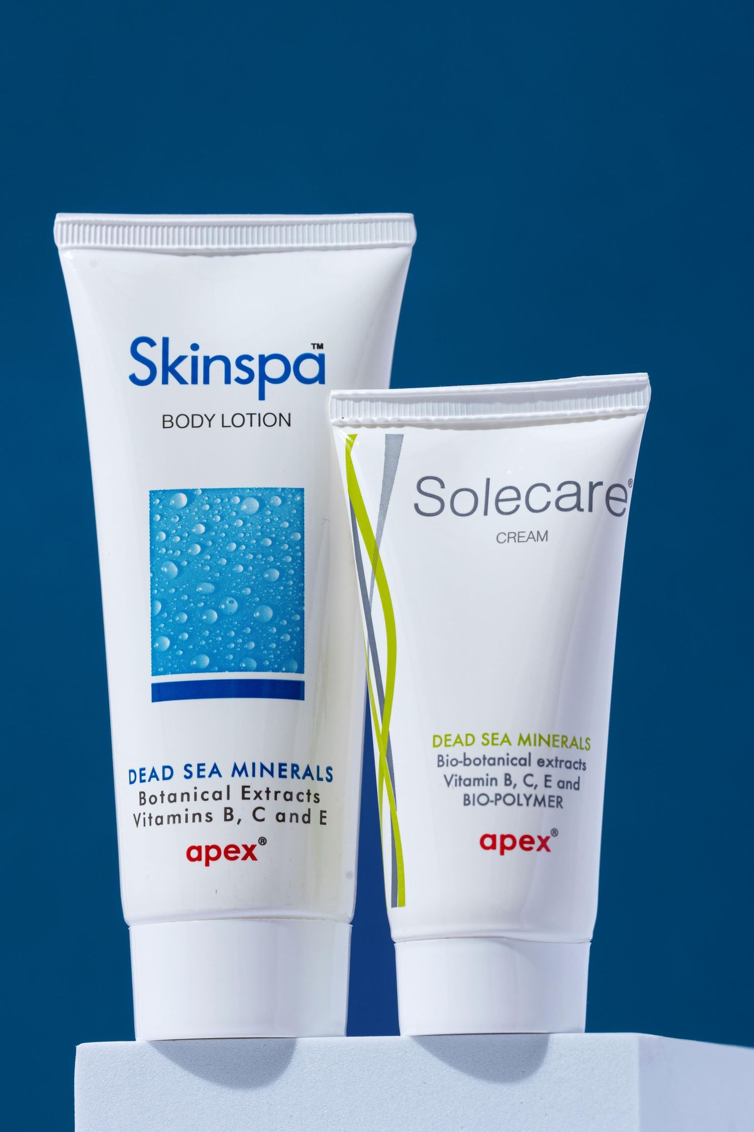 Skinspa body lotion and Solecare cream displayed on white podium against blue backdrop.