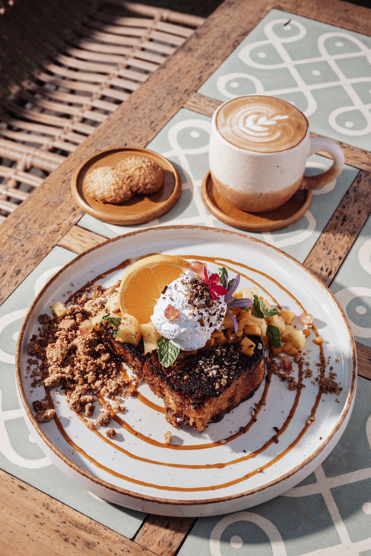 Artfully plated French toast with whipped cream and coffee on a decorative tile surface.