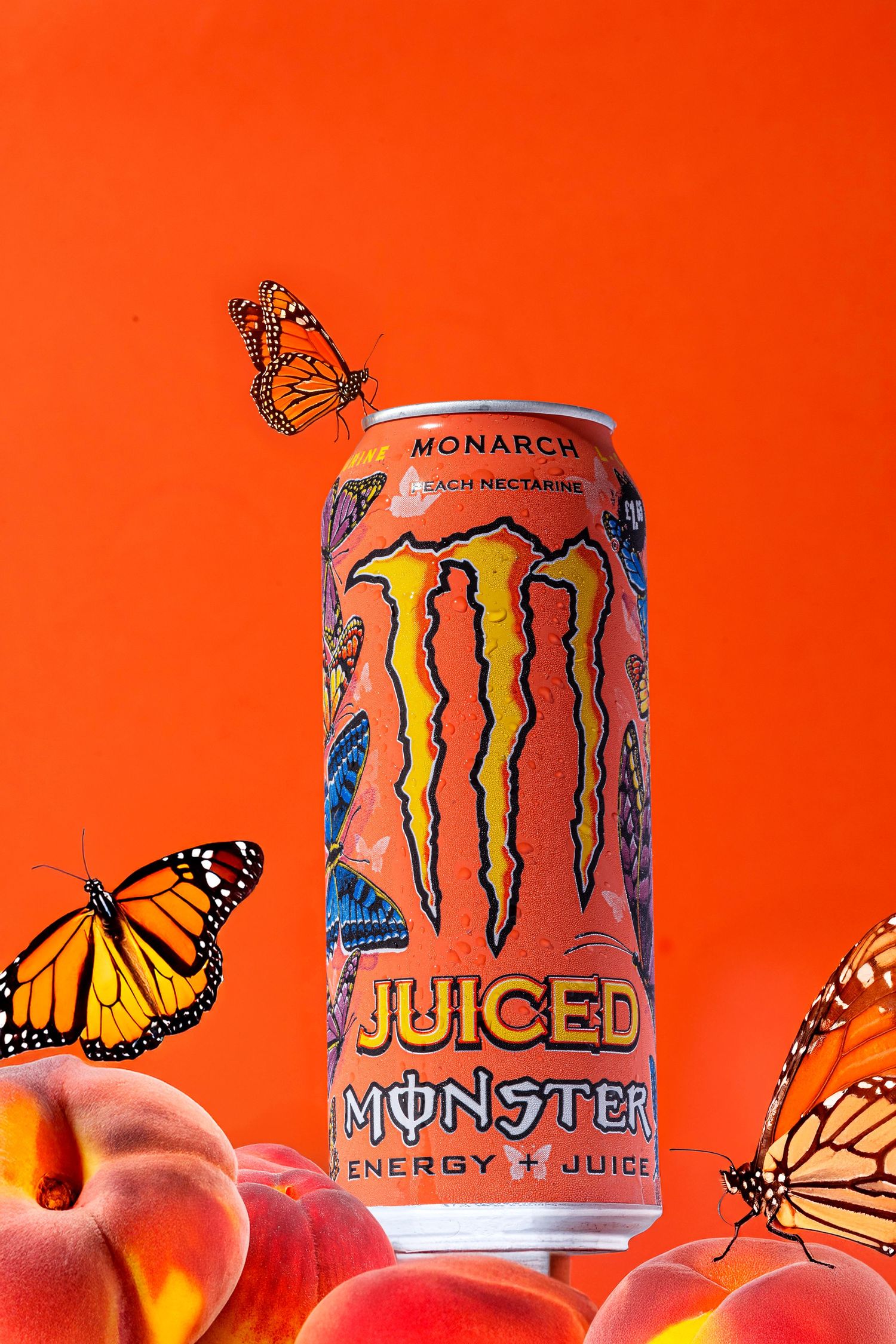 Monarch butterflies surrounding pink Monster energy drink can on orange background.