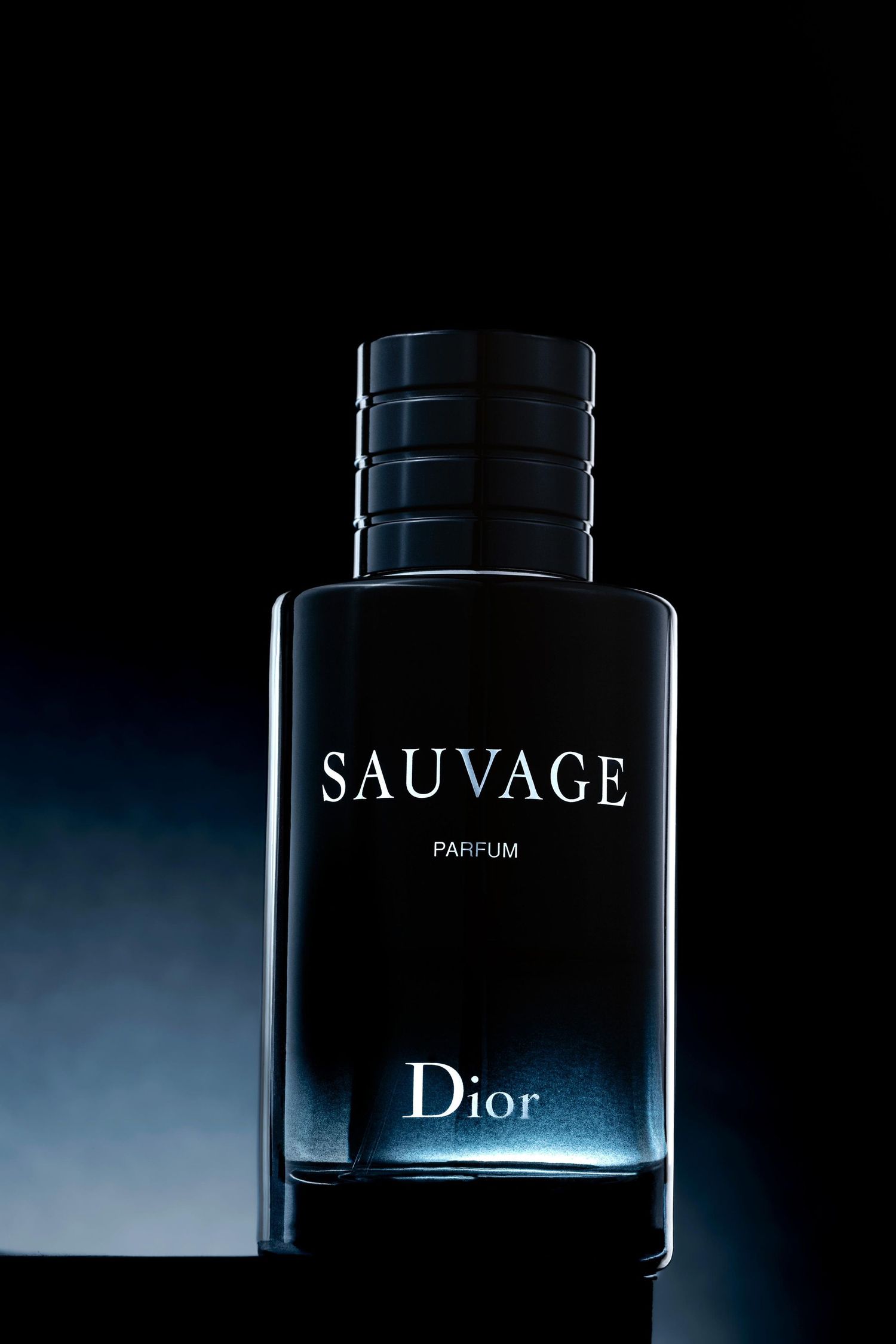 A bottle of Dior Sauvage parfum captured in dramatic lighting against a dark background.