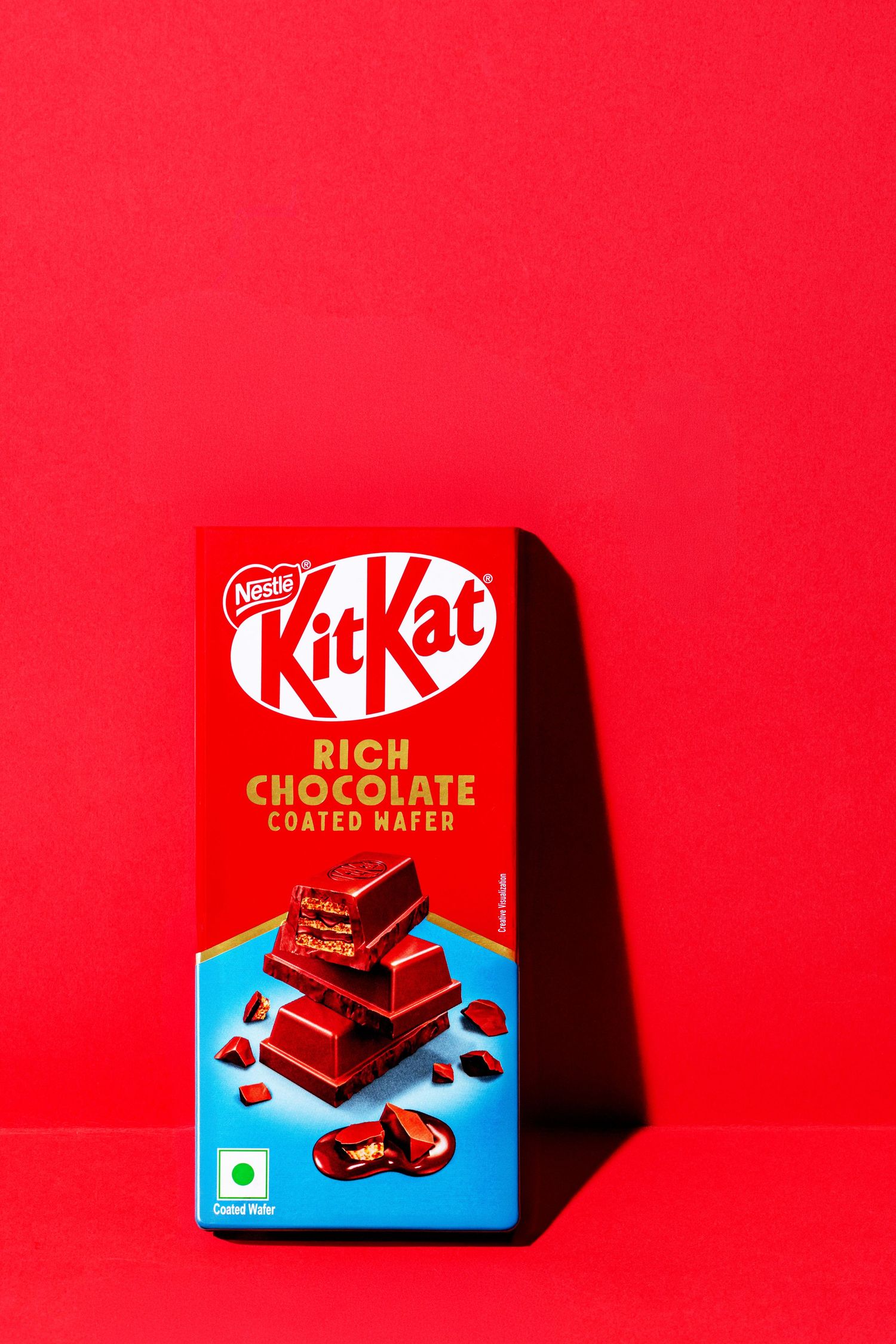 KitKat Rich Chocolate bar package photographed against vibrant red background.