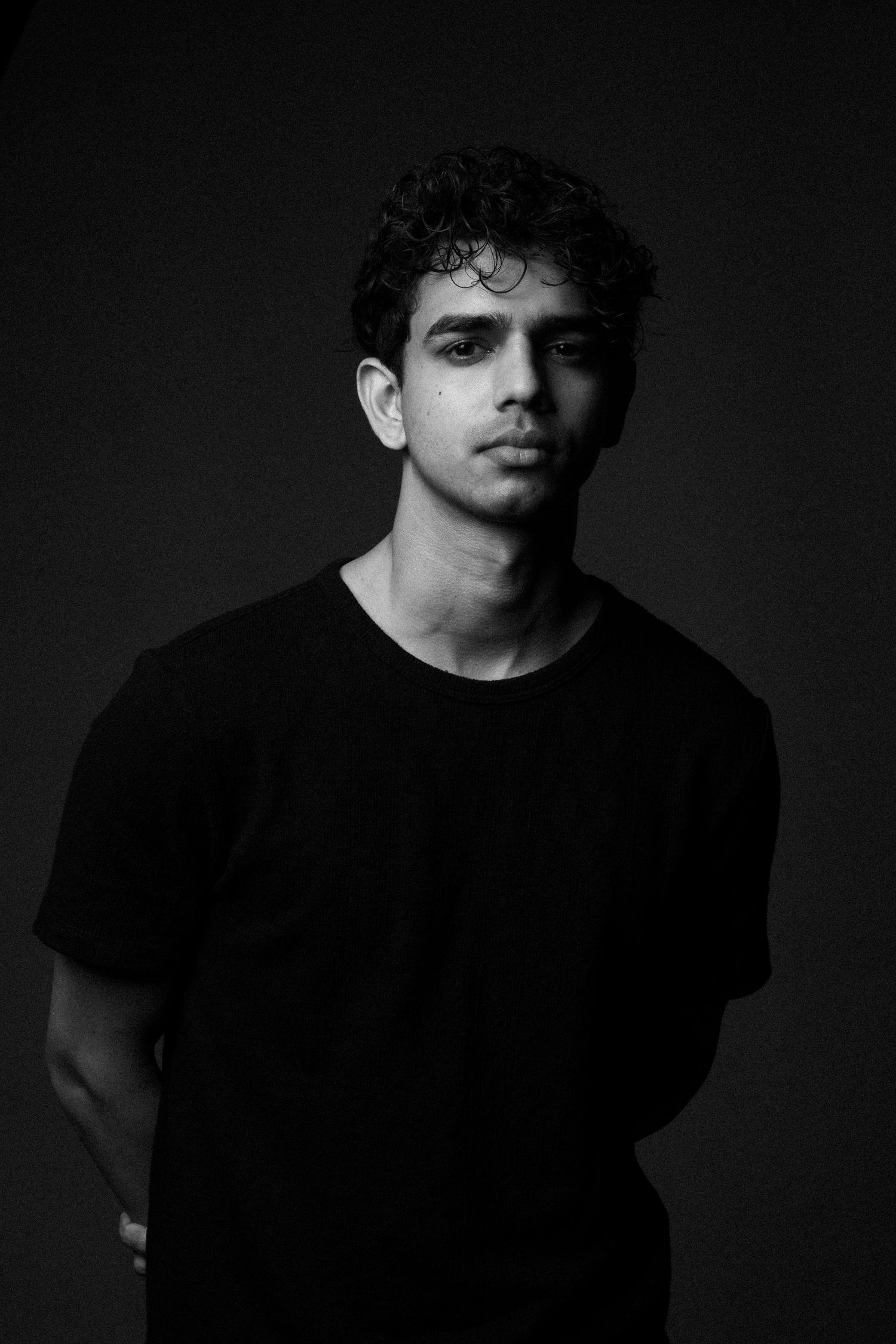 Dramatic black and white portrait against a dark background.