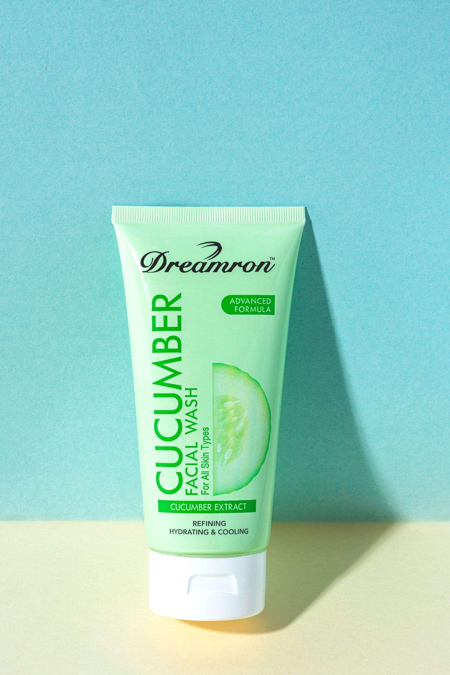 Dreamron cucumber facial wash product tube against turquoise background.