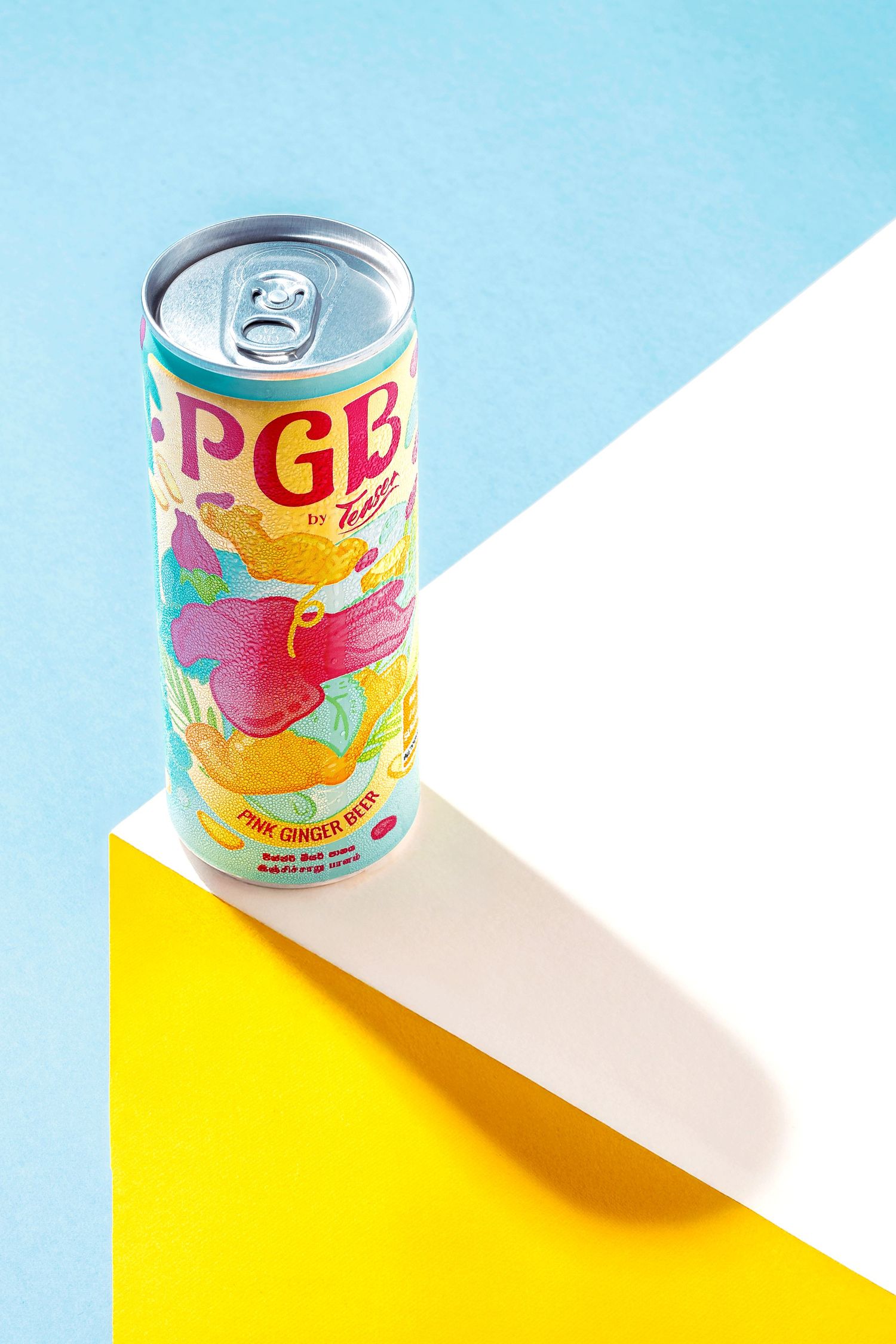 Colorful PGE beverage can photographed on geometric blue and yellow background.