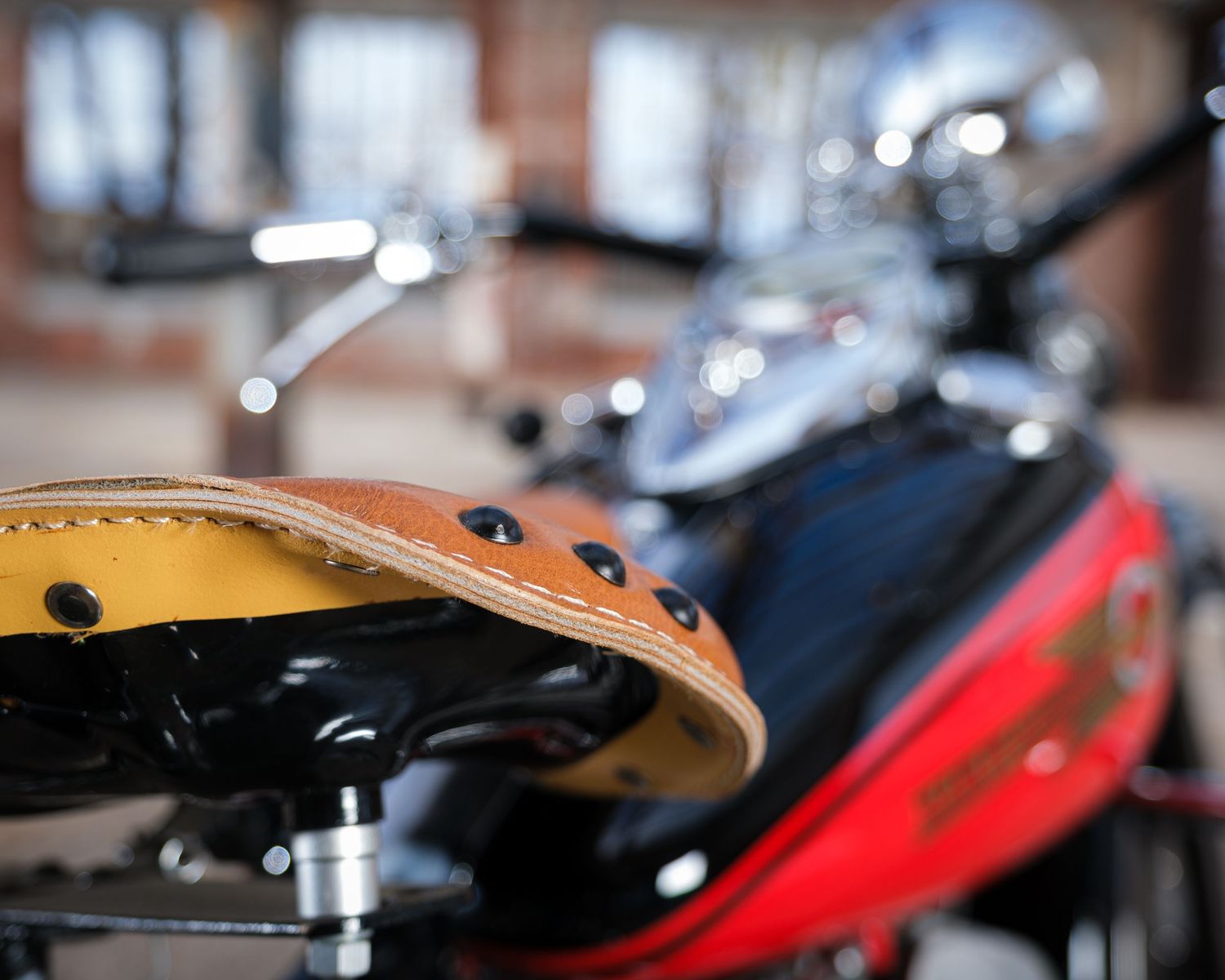 Close-up details of a motorcycle carburetor system showing chrome and black metal parts with blurred background.