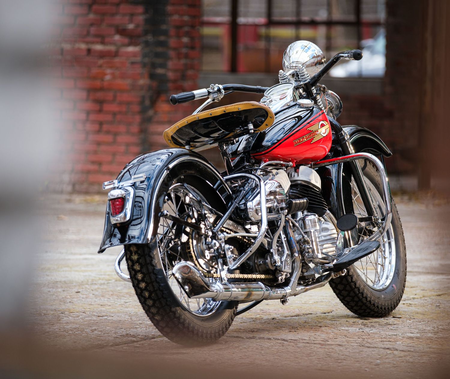 Custom motorcycles displayed in a row against weathered brick wall backdrop.