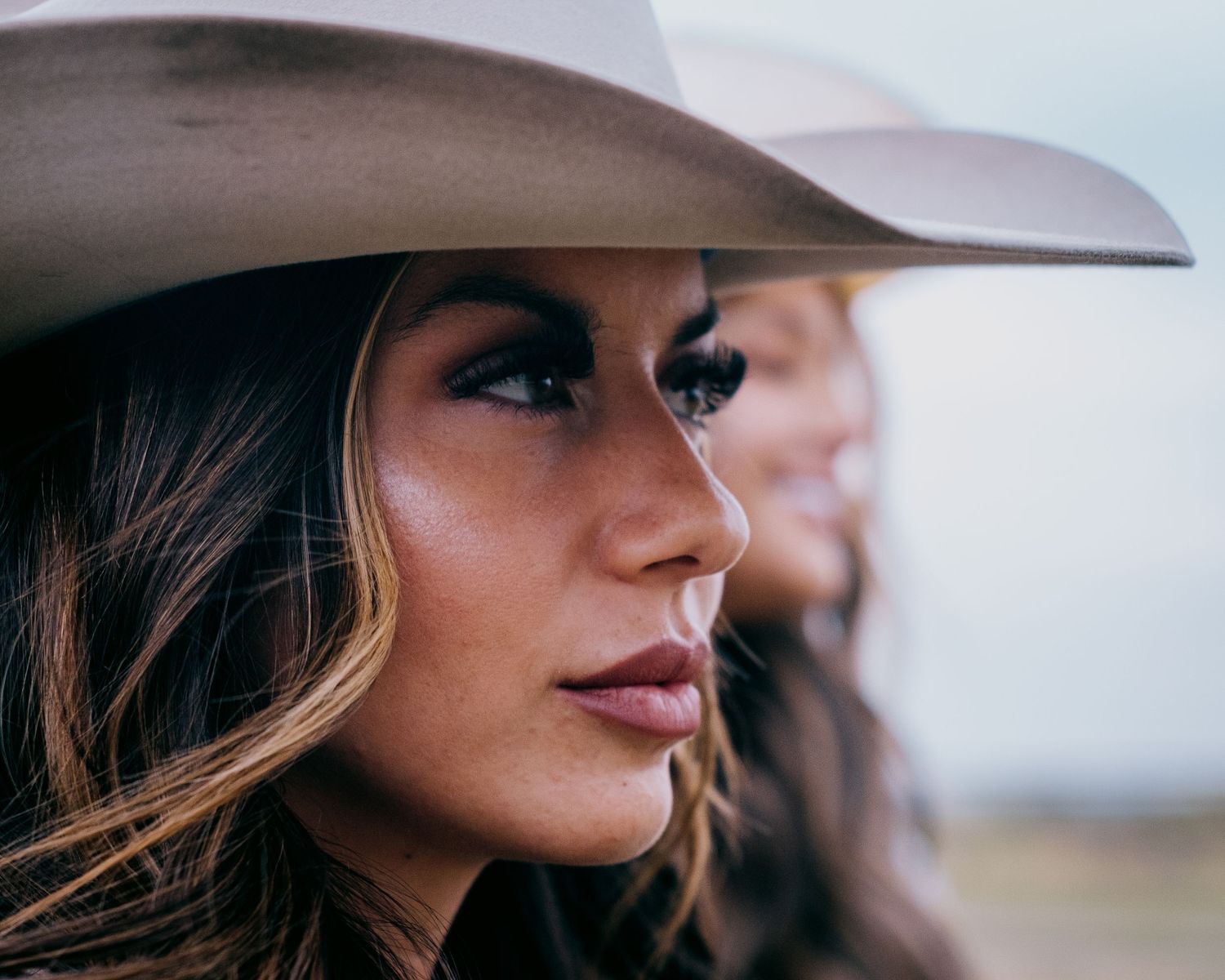 Side profile view of someone wearing a cowboy hat against light background.