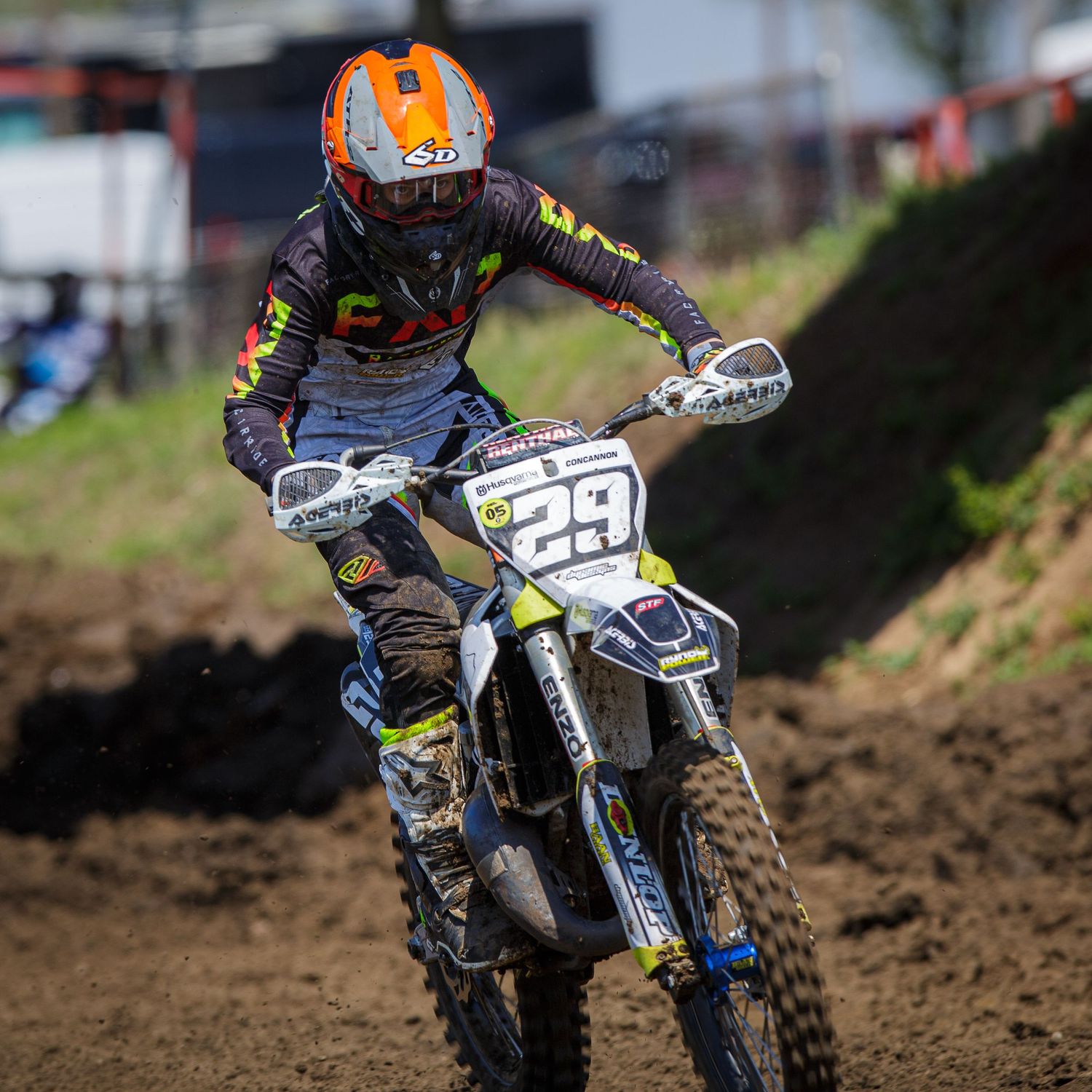Motocross racer tackles dirt track on custom racing bike during competition.