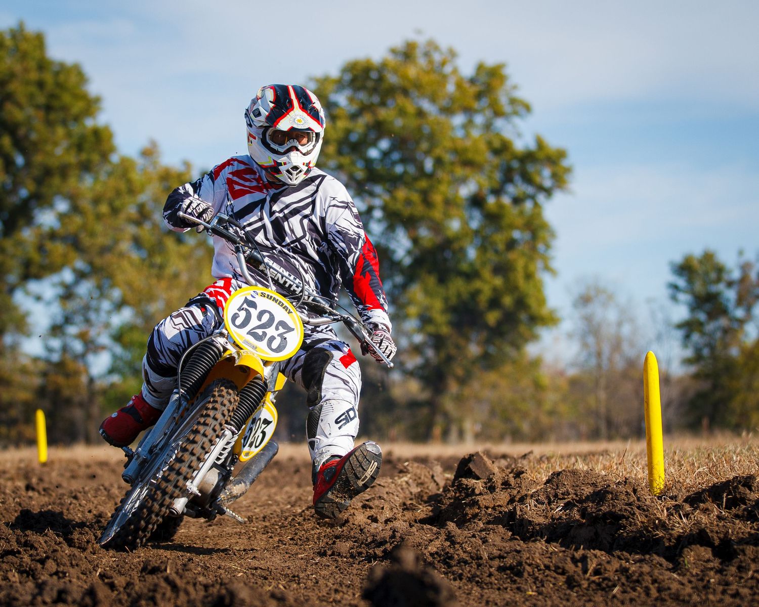 Motocross rider navigates dirt track on race-numbered bike during competition.