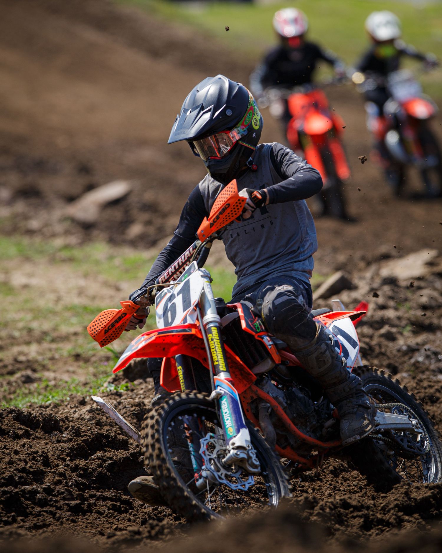 Motocross rider navigates through muddy turn during intense dirt bike race.