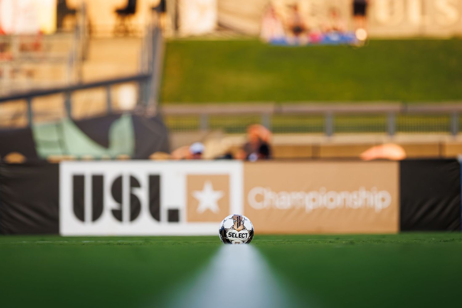 Shallow focus view of USL Championship soccer field with league logo banner visible in background.